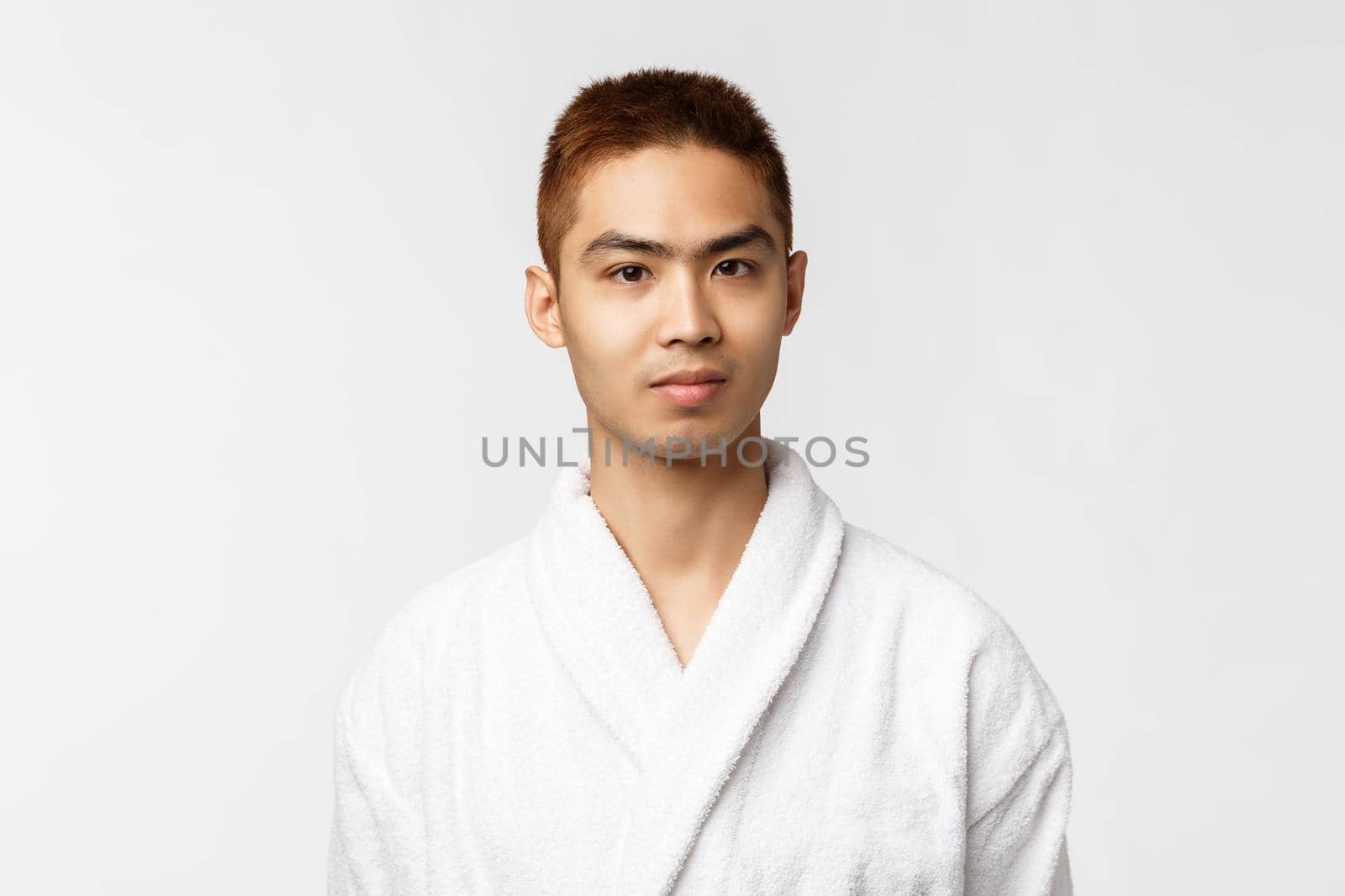 Beauty, spa and leisure concept. Young asian man enjoying vacation, spend weekends on hot springs, wearing bathrobe and smiling camera, feel relaxed at beauty salon, white background by Benzoix