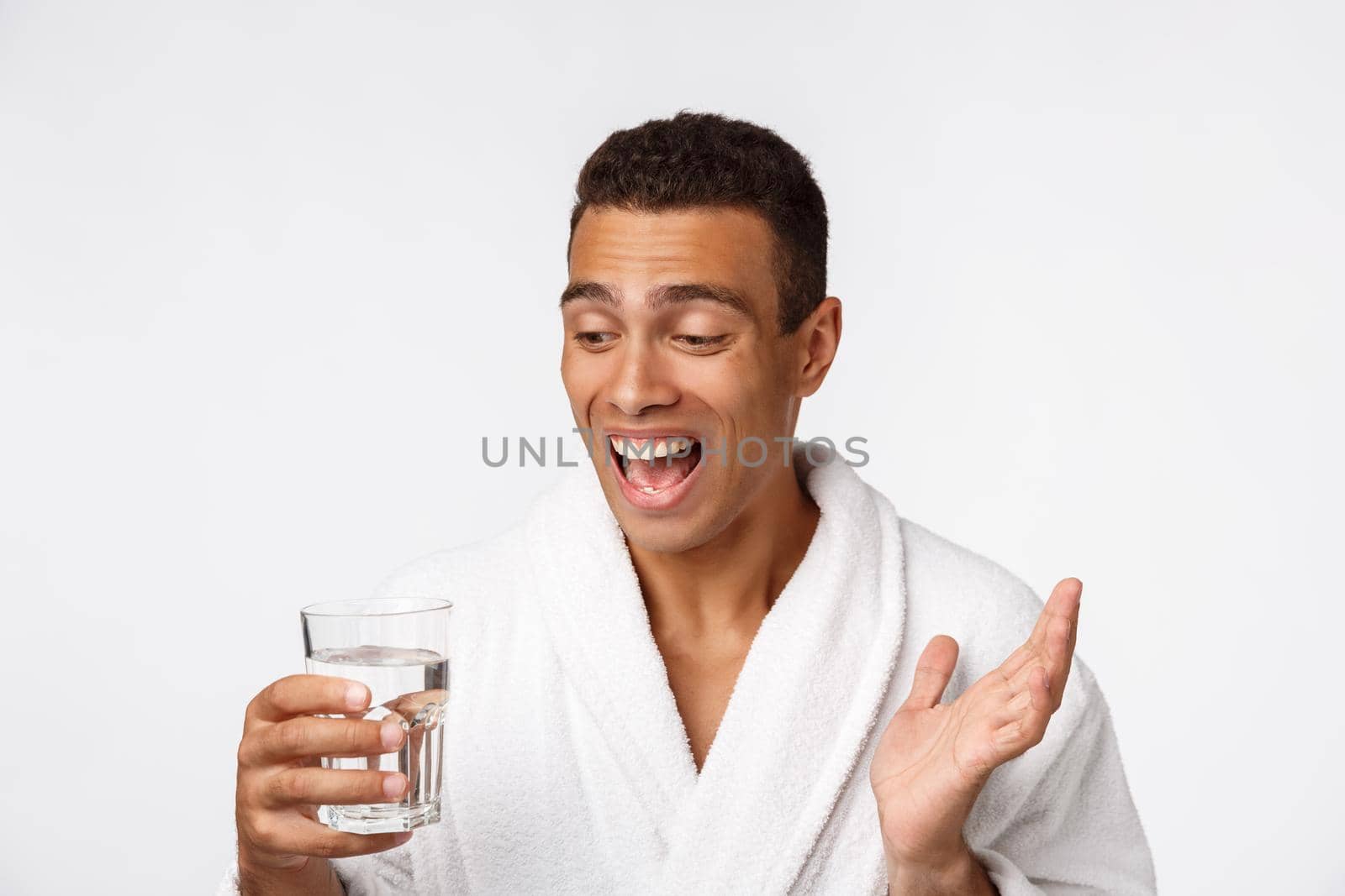 An attractive man drinking a glass of water against white background.