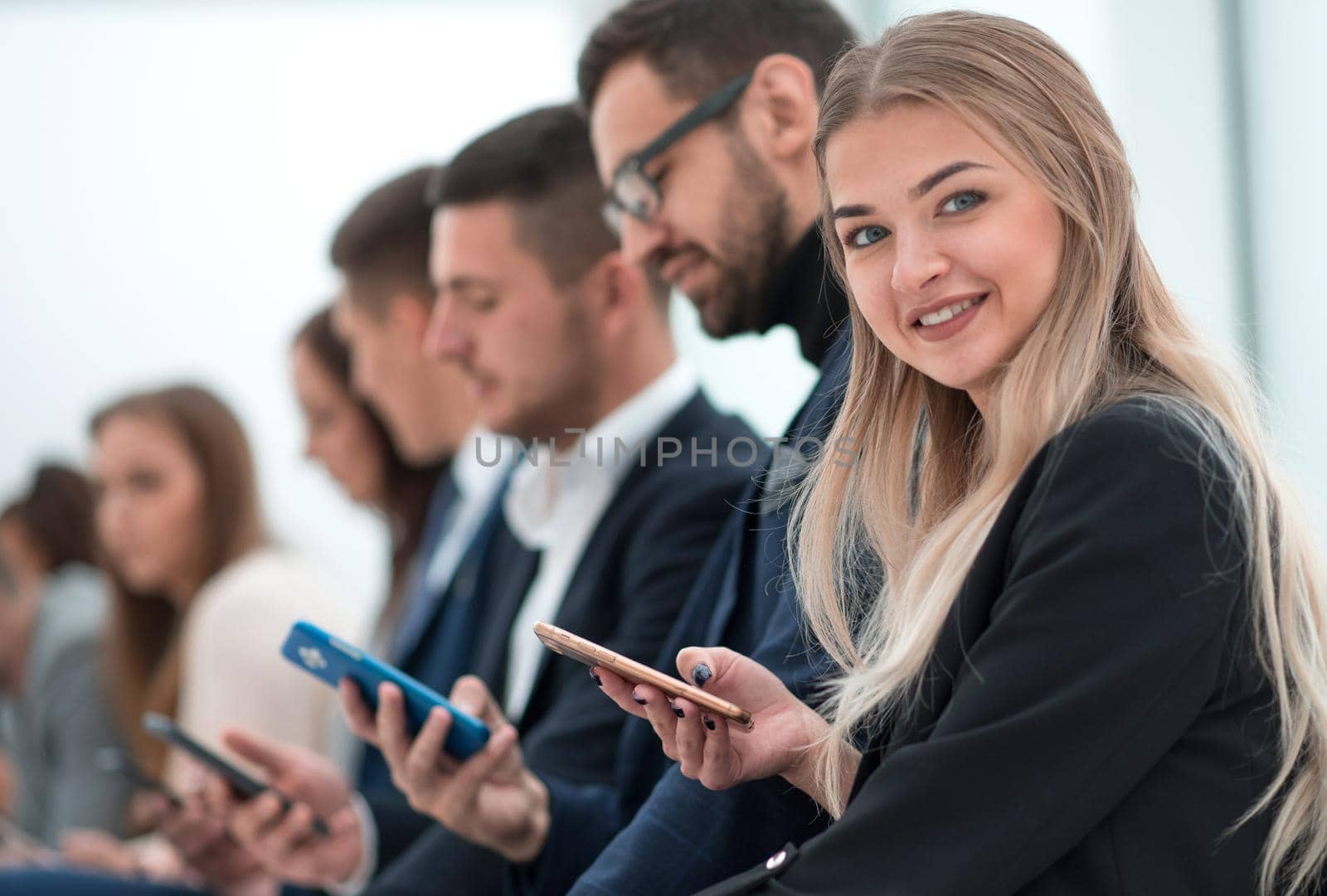 close up. young employees with smartphones sitting in the same row