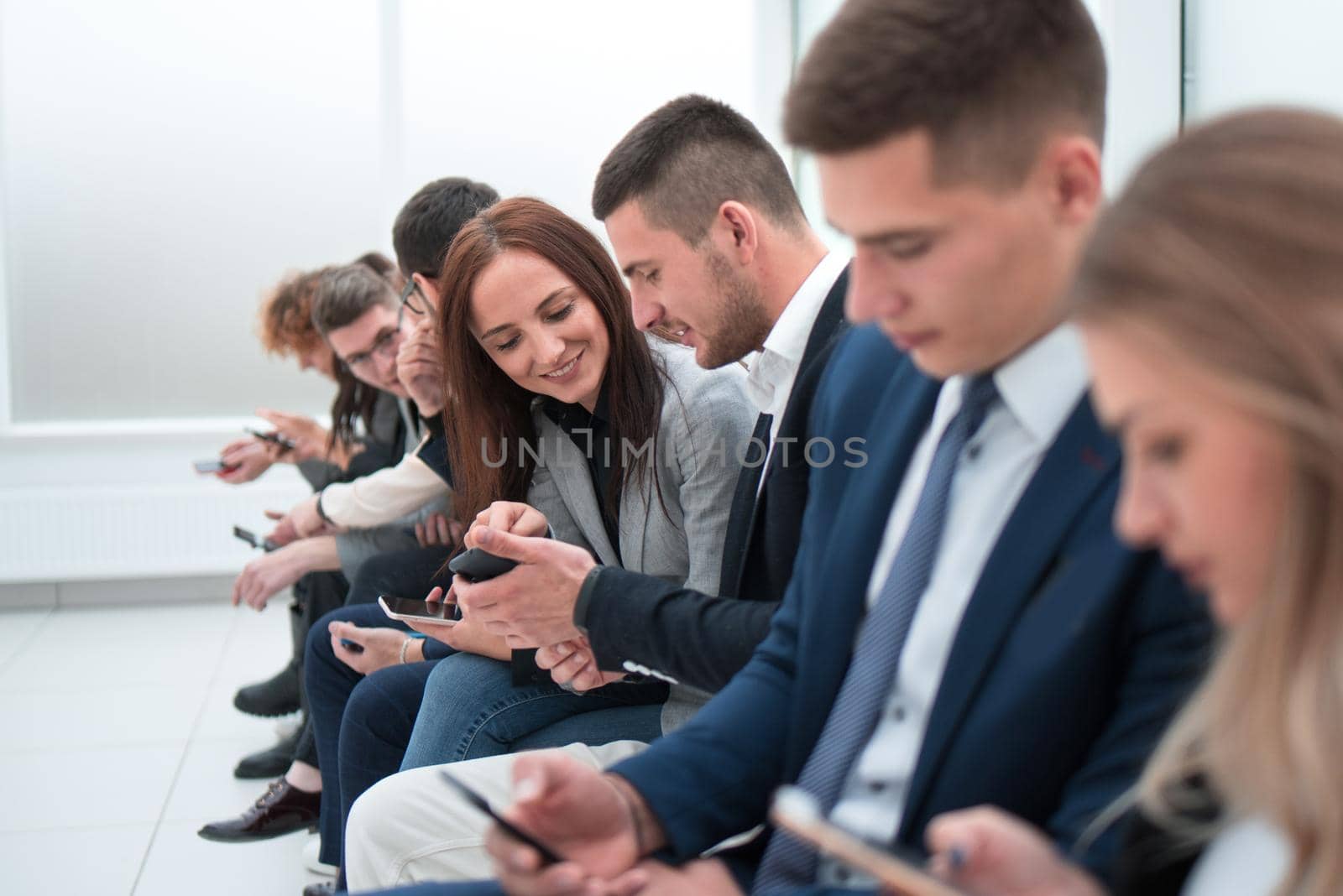 young employees looking at their smartphone screens by asdf