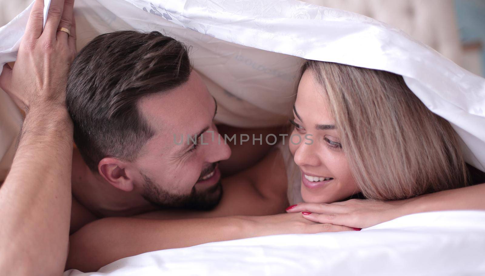 close up. cute loving couple lying under the blanket