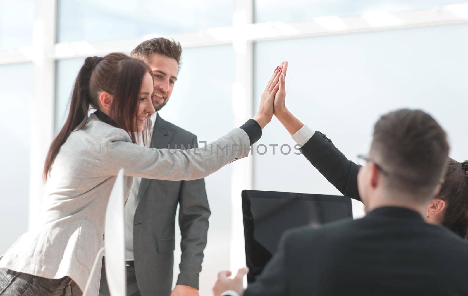young employees giving each other a high five in the workplace. the concept of success