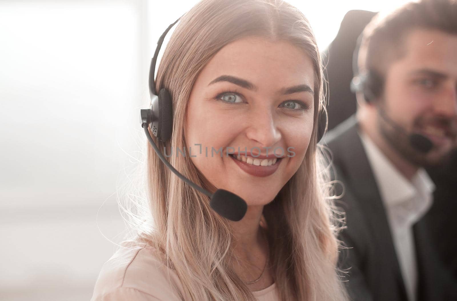 young call center operators on the background of her colleagues by asdf