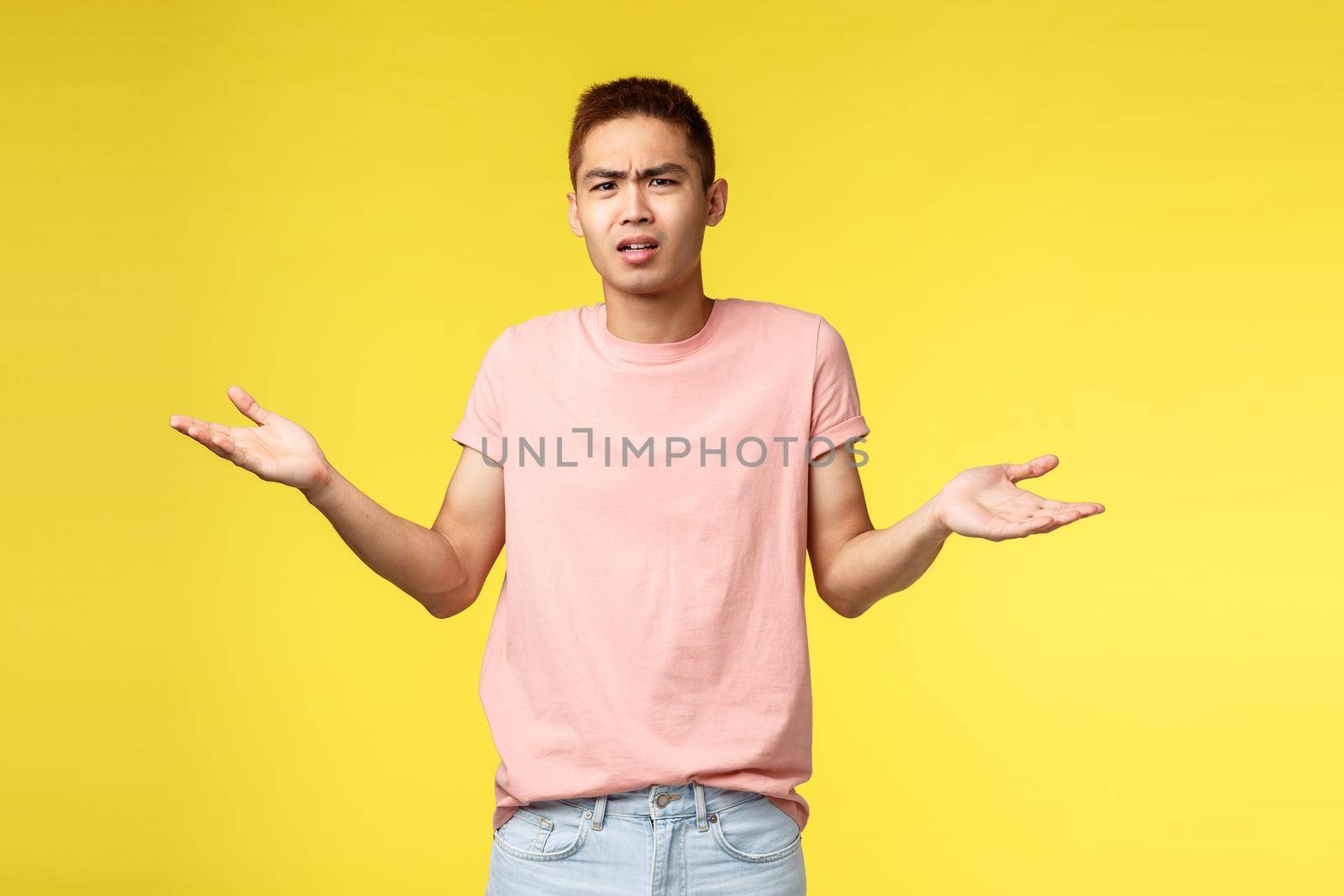 Whats your problem man. Portrait of displeased, frustarted young asian guy look bothered and confused, shrugging, spread hands sideways, cant understand what happened, stand yellow background.