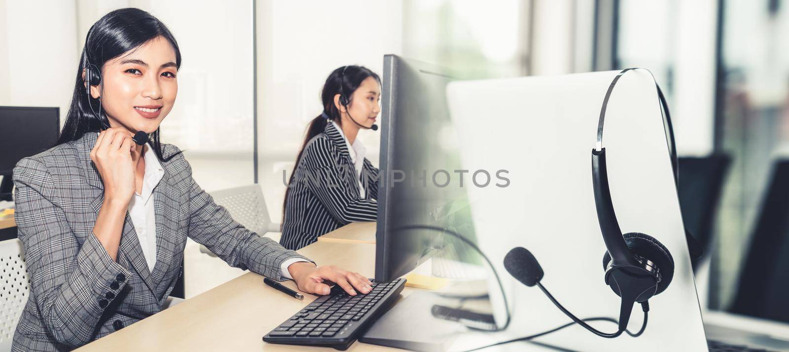 Business people wearing headset working in office to support remote customer or colleague. Call center, telemarketing, customer support agent provide service in broaden view .