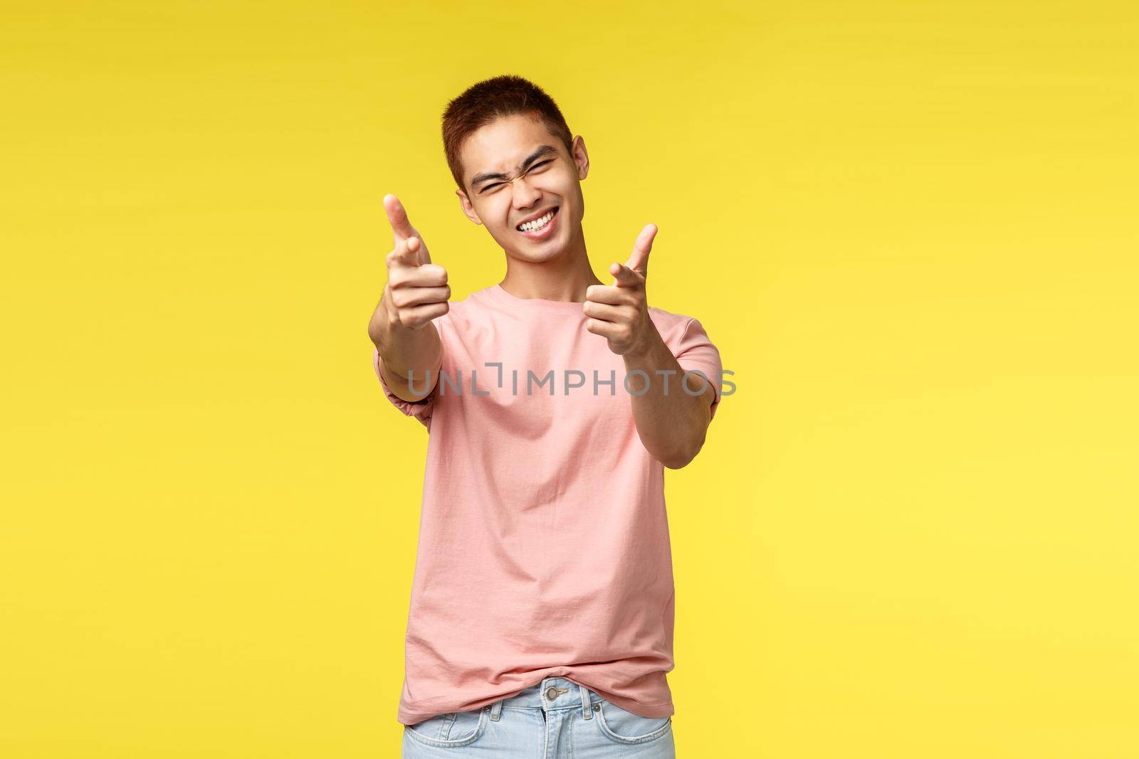 Lifestyle, travel and people concept. You rock man. Portrait of enthusiastic handsome asian guy pointing fingers at camera and smiling, picking or recruiting to his team, stand yellow background by Benzoix