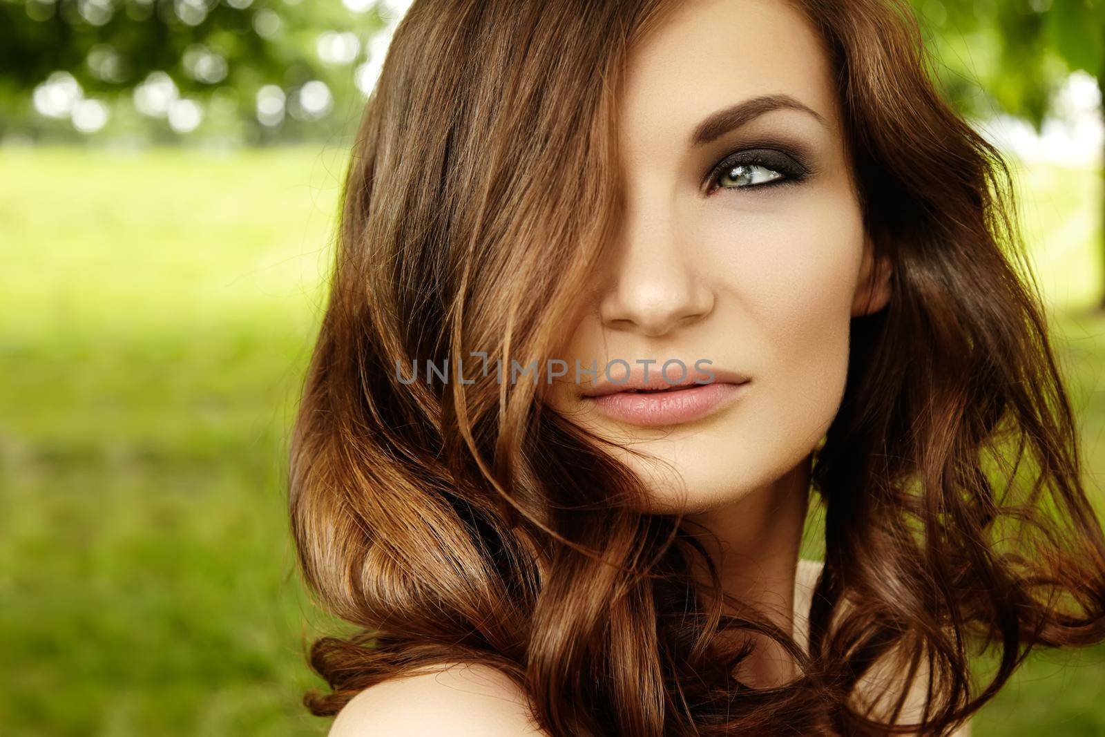 Beautiful woman with fashion makeup, volume hair style on green background summer nature. Sexy hairstyle, clean shiny skin