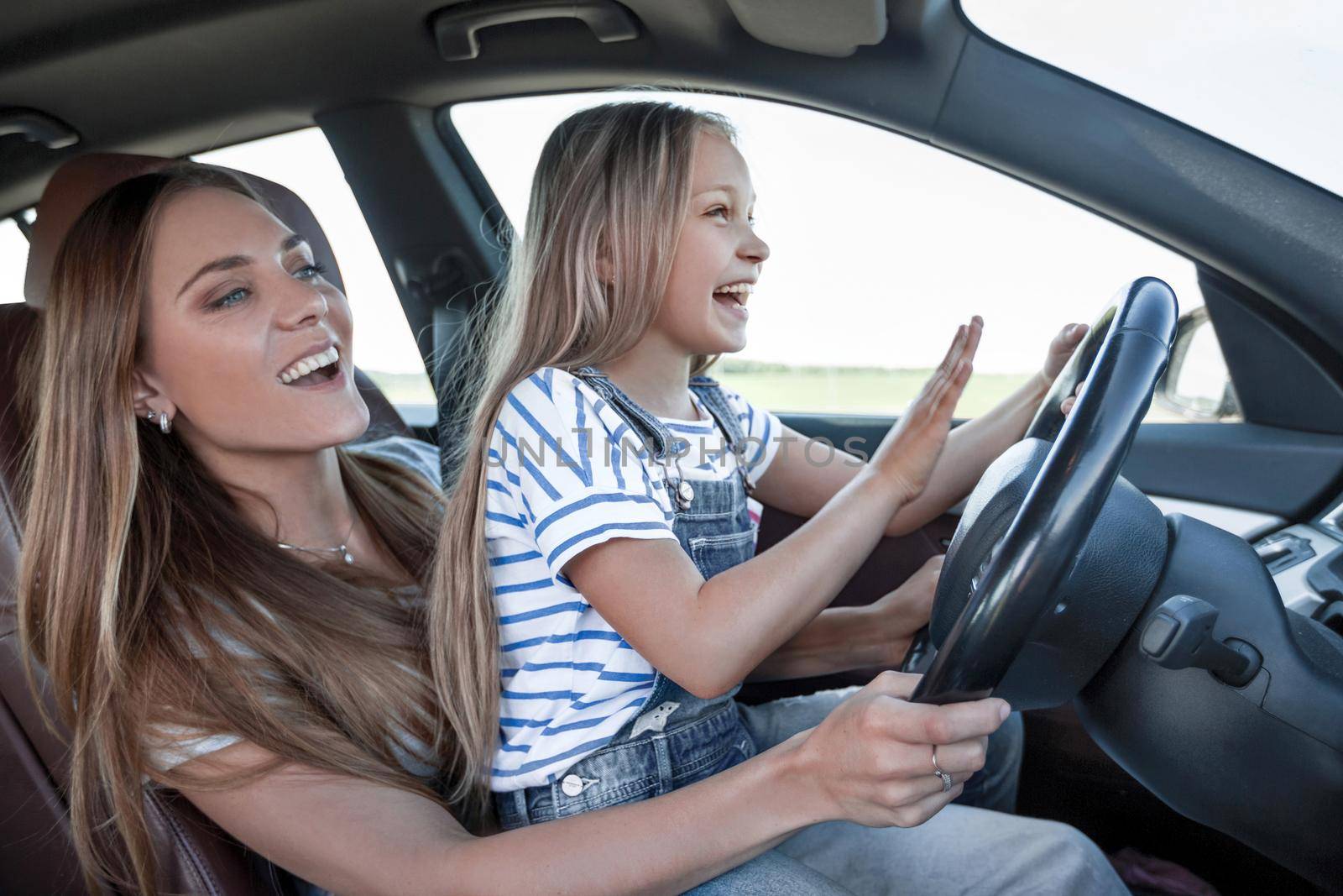 mom teaches her little daughter to drive.the concept of parenting