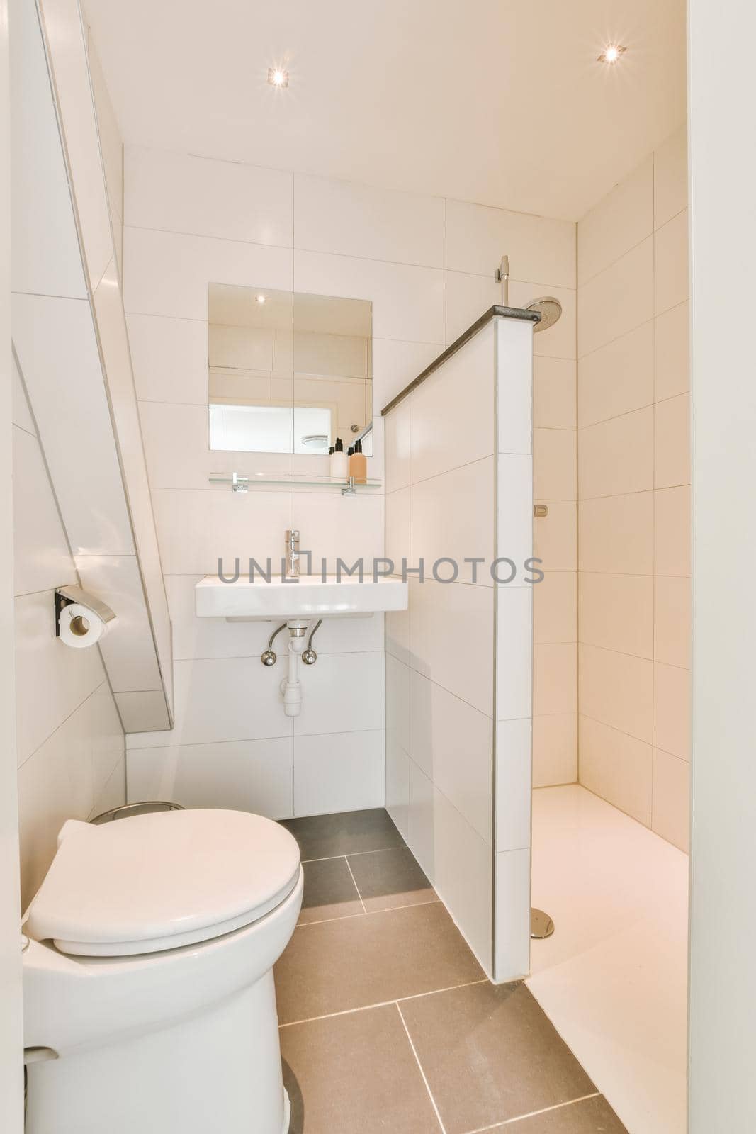 Wall hung toilet and small sink in corner in lavatory room with beige tile