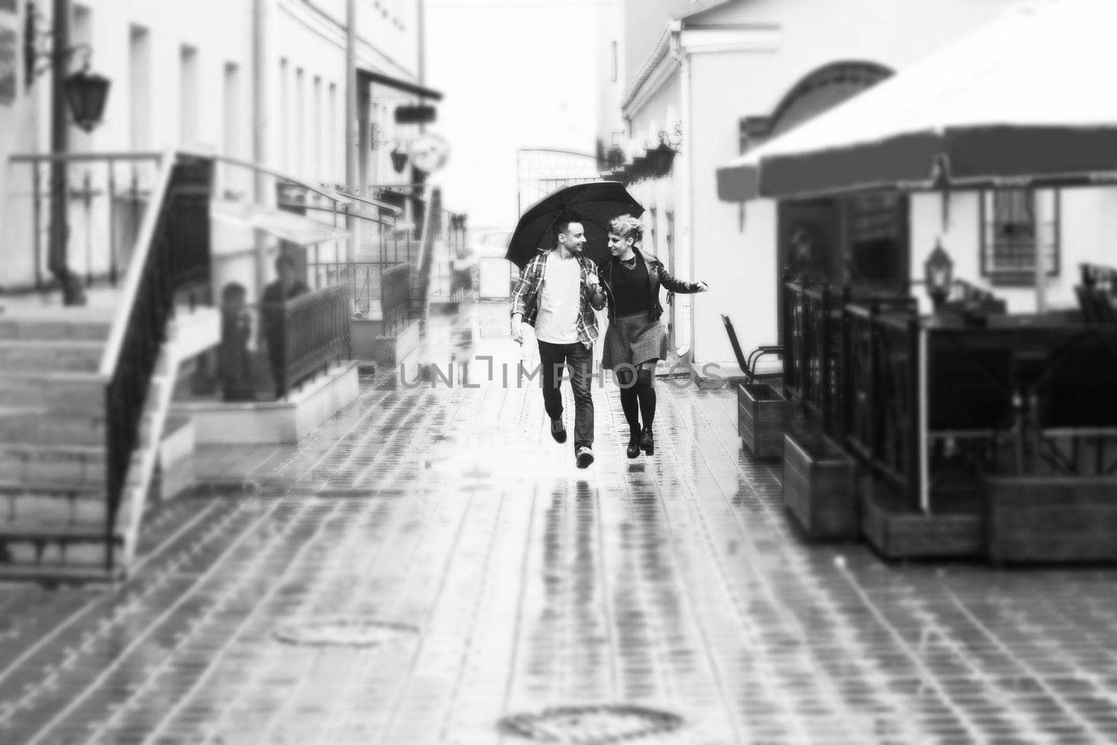 concept of love: loving couple under an umbrella walking down the street of the city.black-and-white photo in retro style by SmartPhotoLab