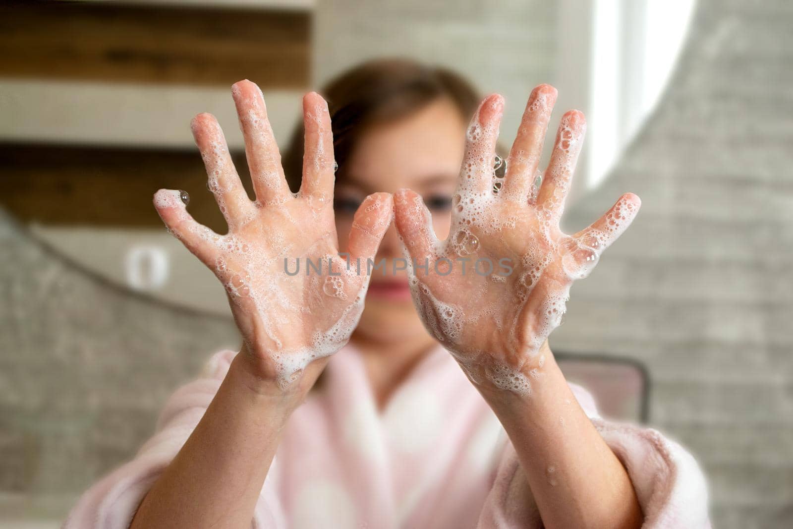 Little girl washing hands with water and soap in bathroom. Happy kid showing soapy palms. Hands hygiene and virus infections prevention. . High quality photo