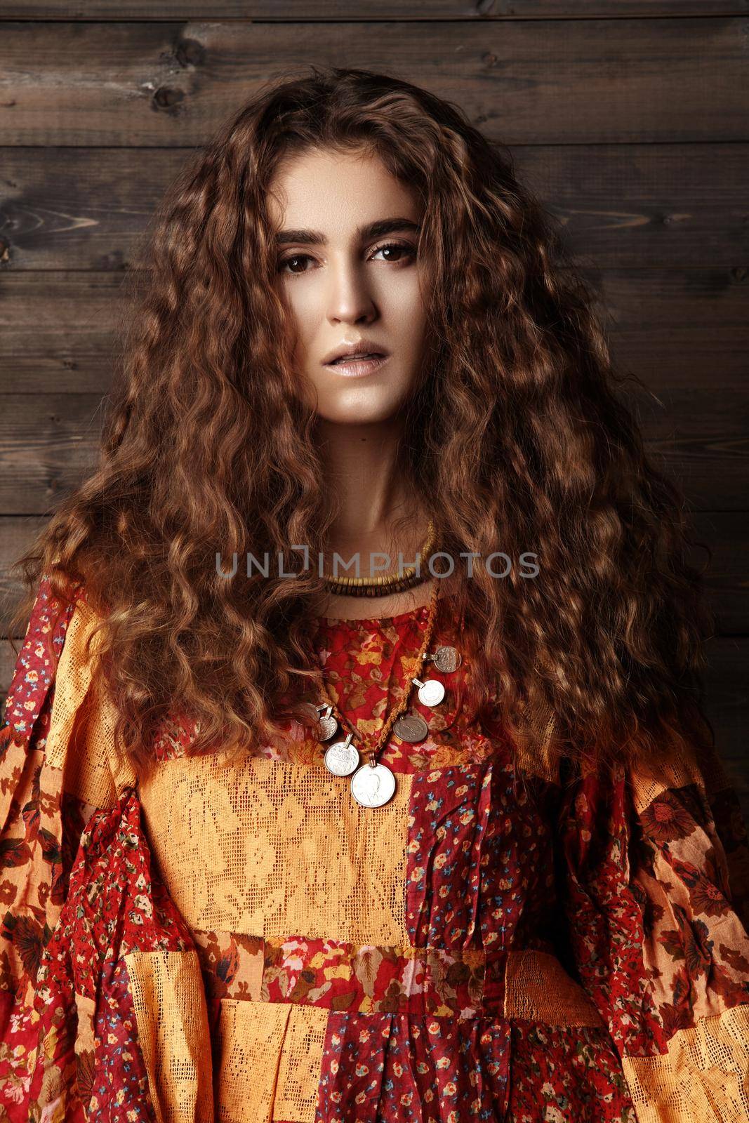 Beautiful young woman with long curly hairstyle, fashion jewelry with long brunette hair. Sexy girl in vogue style. Pretty arabian beauty portrait of female face. Indian style clothes, long dress