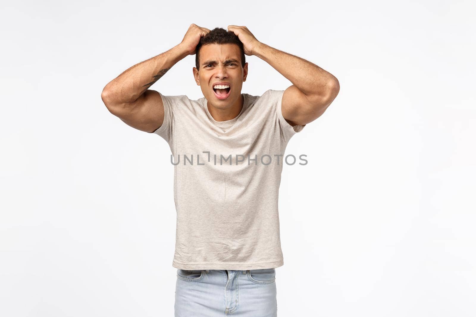 Disappointed athletic man in t-shirt, grab head and pull hair bothered, frowning grimacing shocked and frustrated, lost huge money, feel betrayed or let down, standing distressed white background.