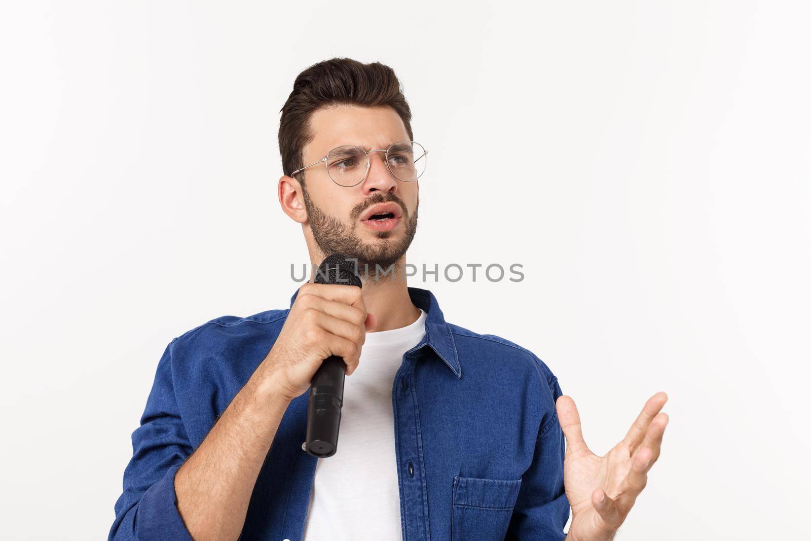 Portrait of an excited young man in t-shirt isolated over gray backgound, singing