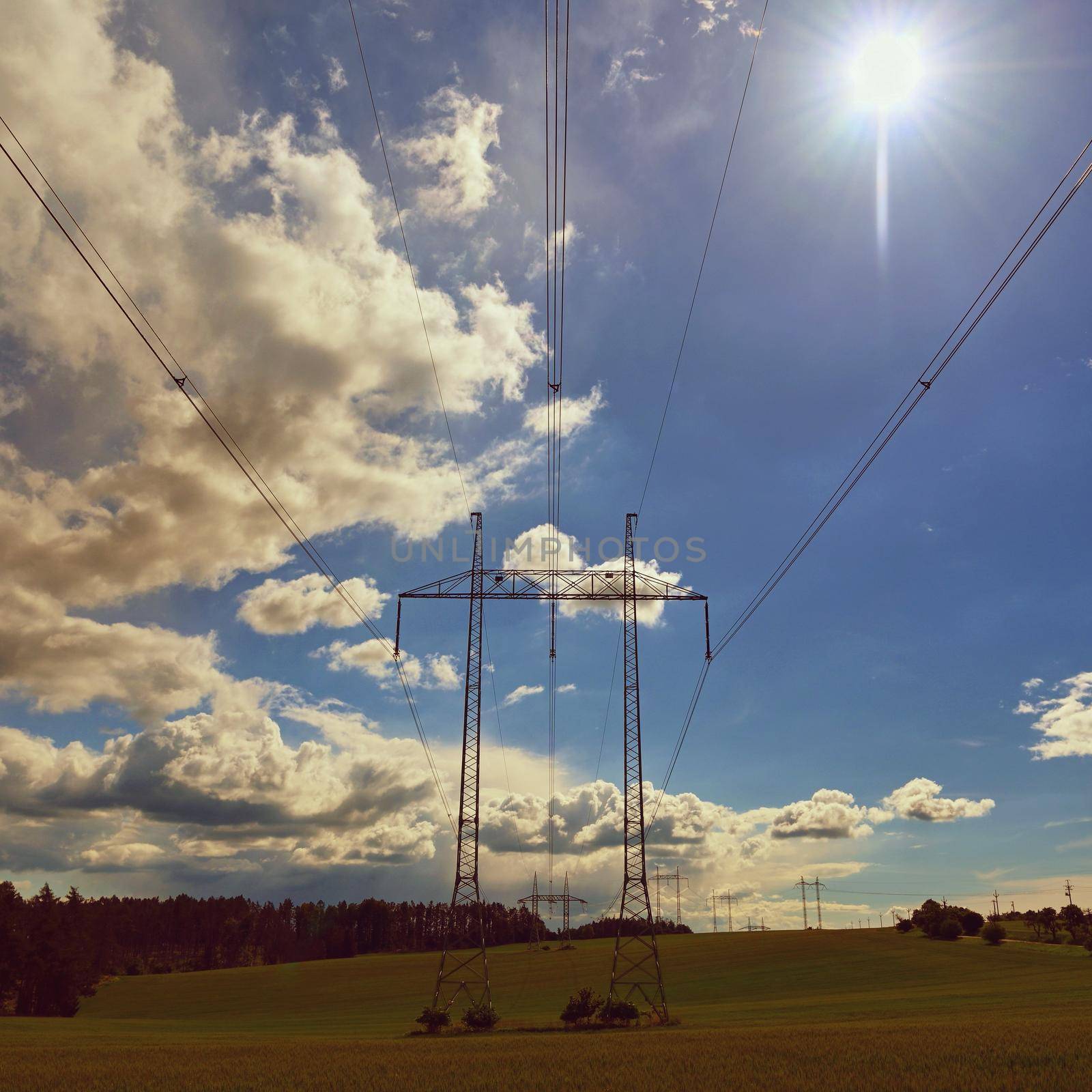 High voltage pylons - Blue sky with clouds and sun in nature. Concept for technology and industry. Further rising electricity and energy prices - the energy crisis caused by the war between Russia and Ukraine. 
