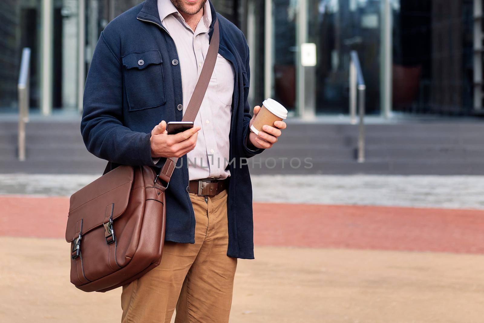 unrecognizable man consulting his phone at the entrance of the office building, concept of business and communication, copy space for text