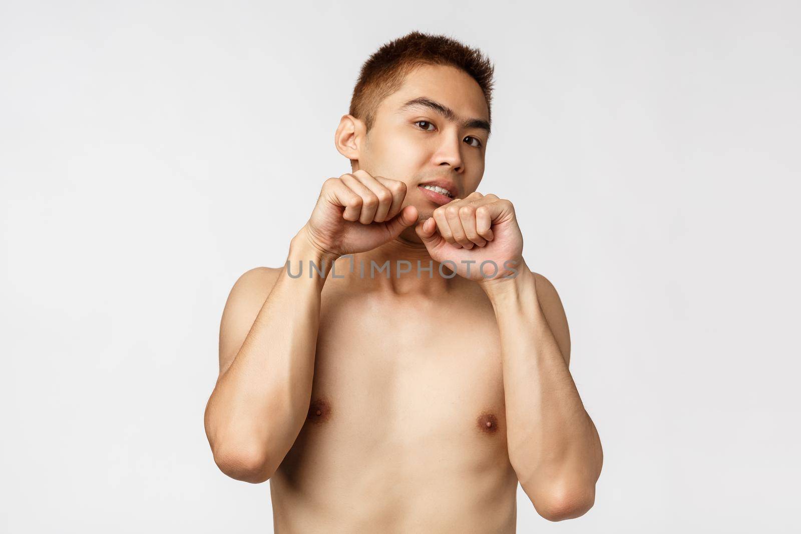 Beauty, people and home concept. Cute asian man with naked torso acting like kitten, making nya kawaii gesture imitating paws, look camera upbeat, standing white background.