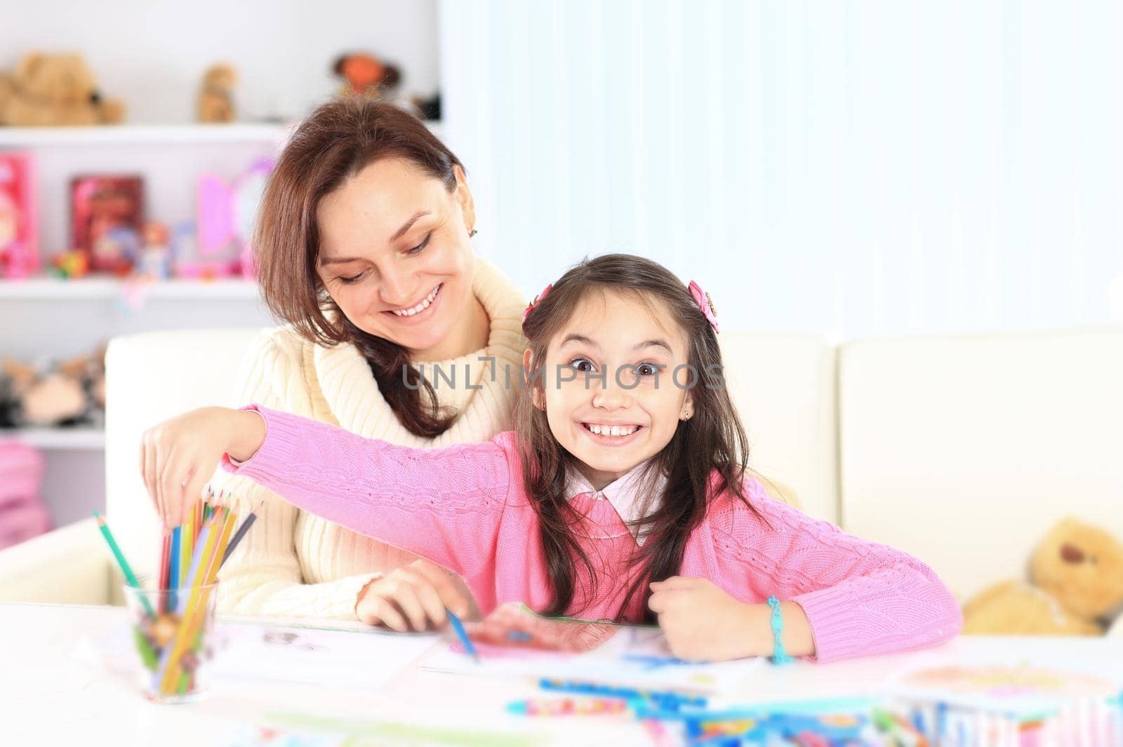 Beautiful girl draws with her mother at home