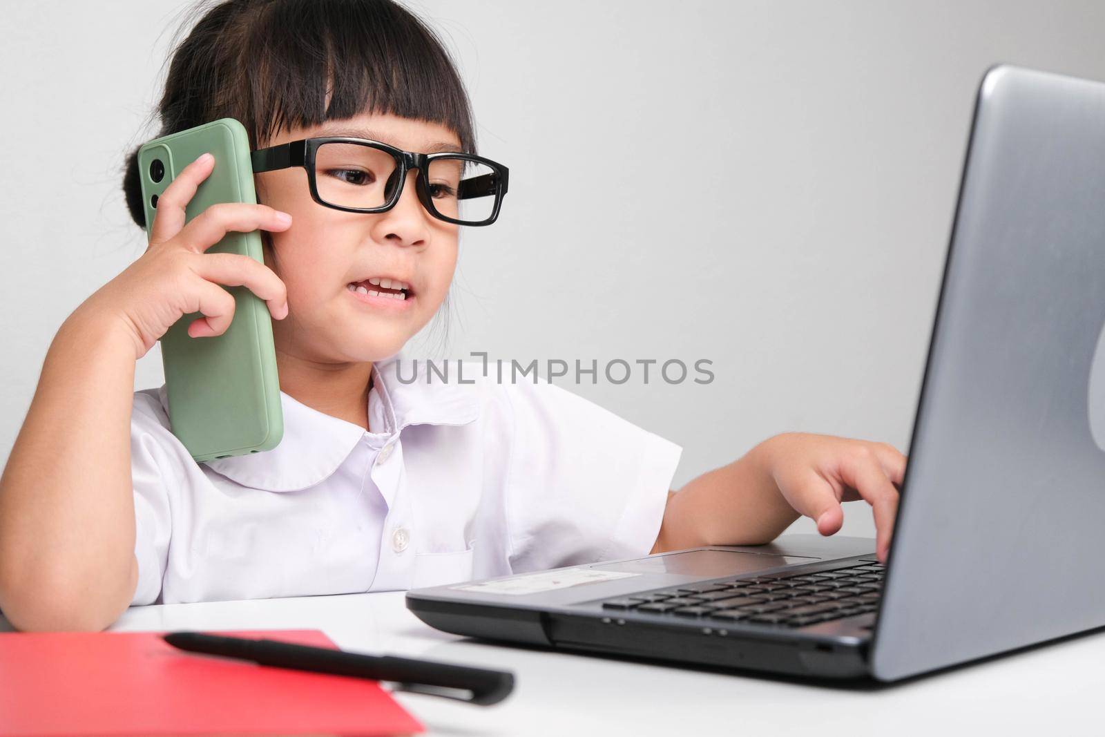 Little business woman with laptop working in office while talking on the phone Children and business concepts by TEERASAK