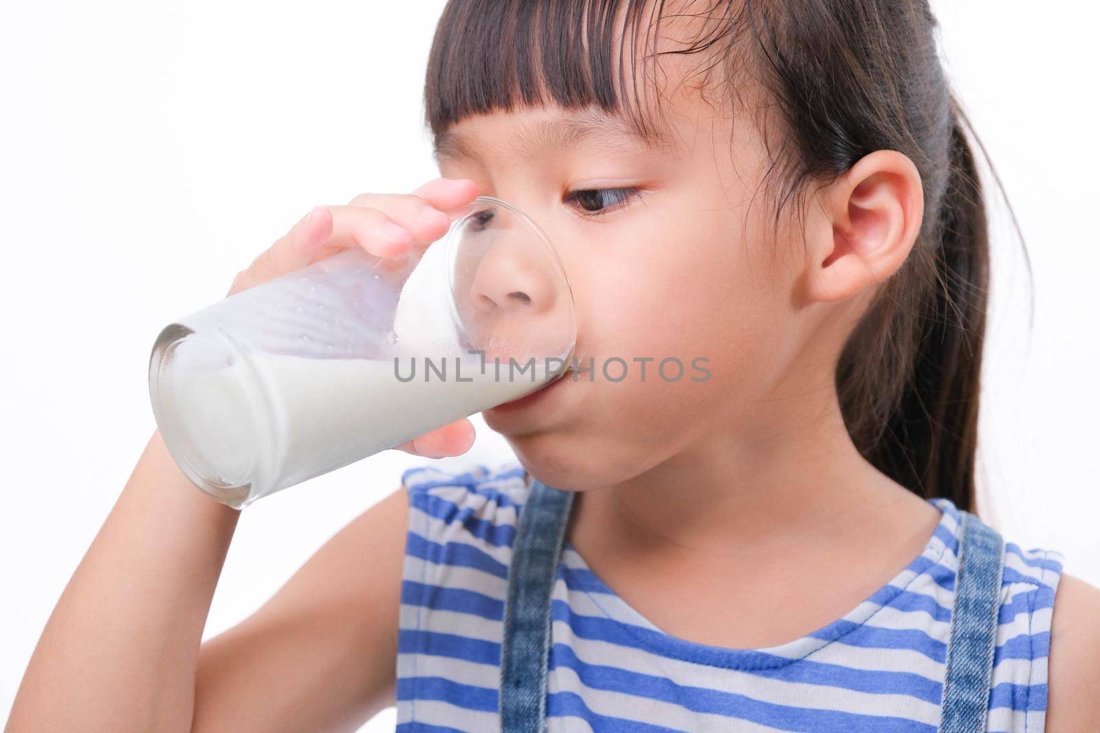 Cute little girl drinking milk from a glass isolated on white background. Little girls enjoy drinking milk before going to school.
