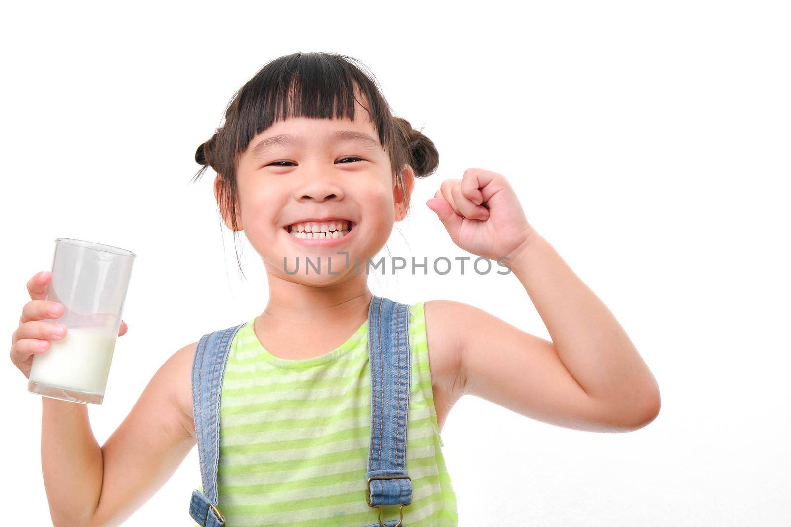 Portrait of a cute Asian little girl holding a glass of milk isolated on white background. Small girl at home with smiling face, feeling happy enjoying drinking milk and looking at camera. by TEERASAK