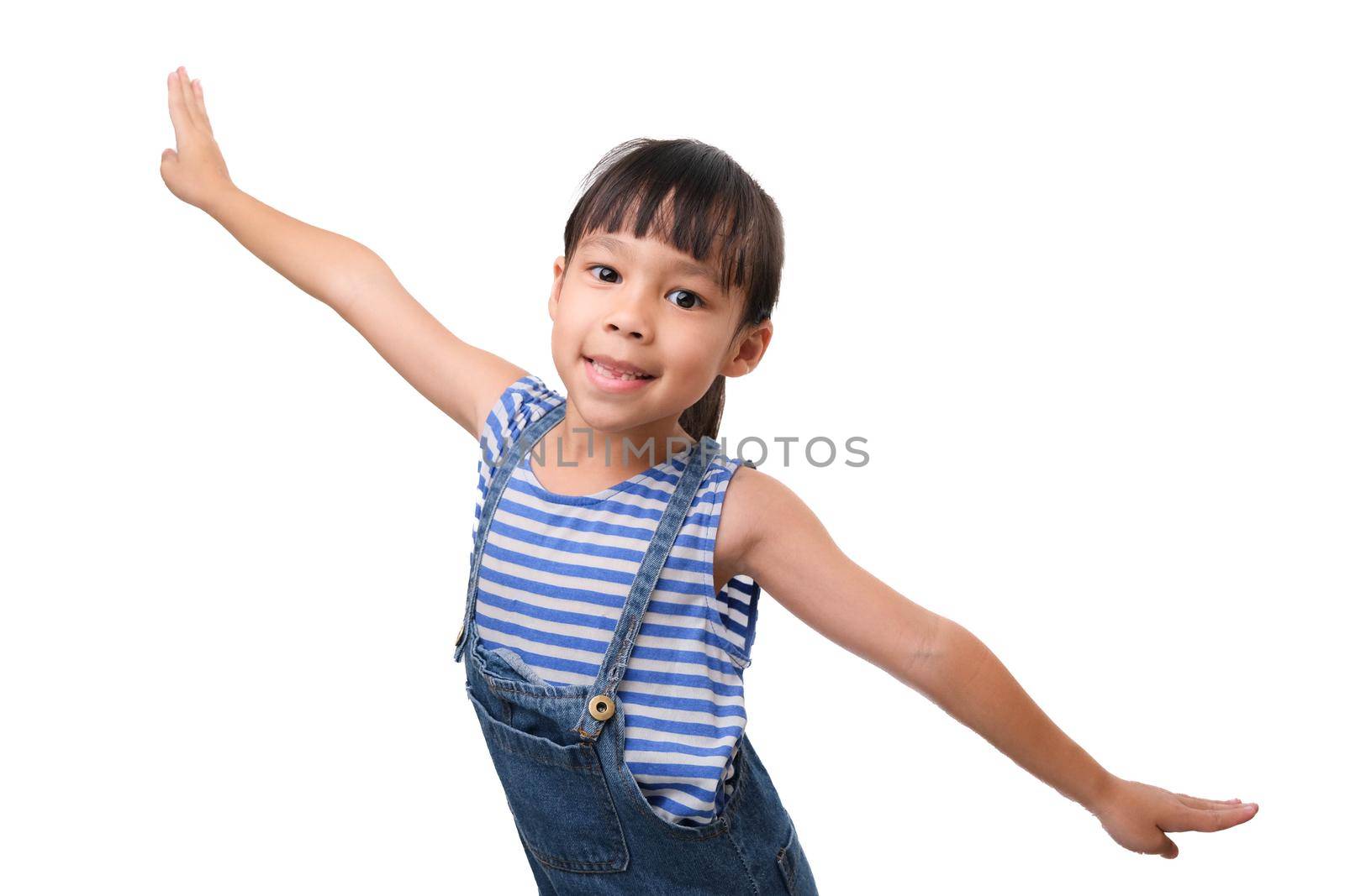 Happy little carefree girl smiling and balancing standing on one leg with her arms outstretched as if flying on a white background. by TEERASAK