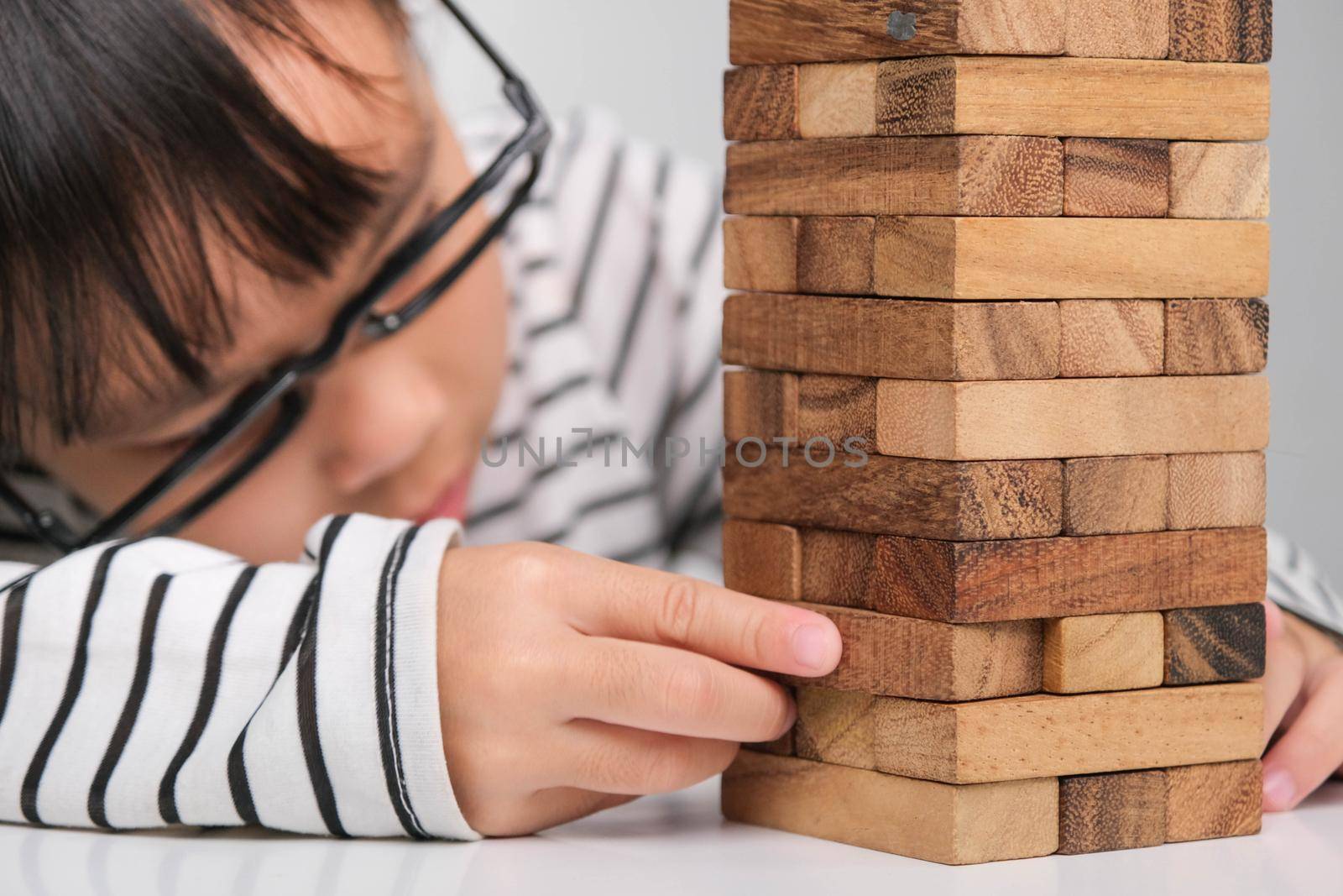 Asian children playing wooden blocks on table at home. Cute little girl having fun playing with building blocks. Wooden block tower building game. Toys for the development of children