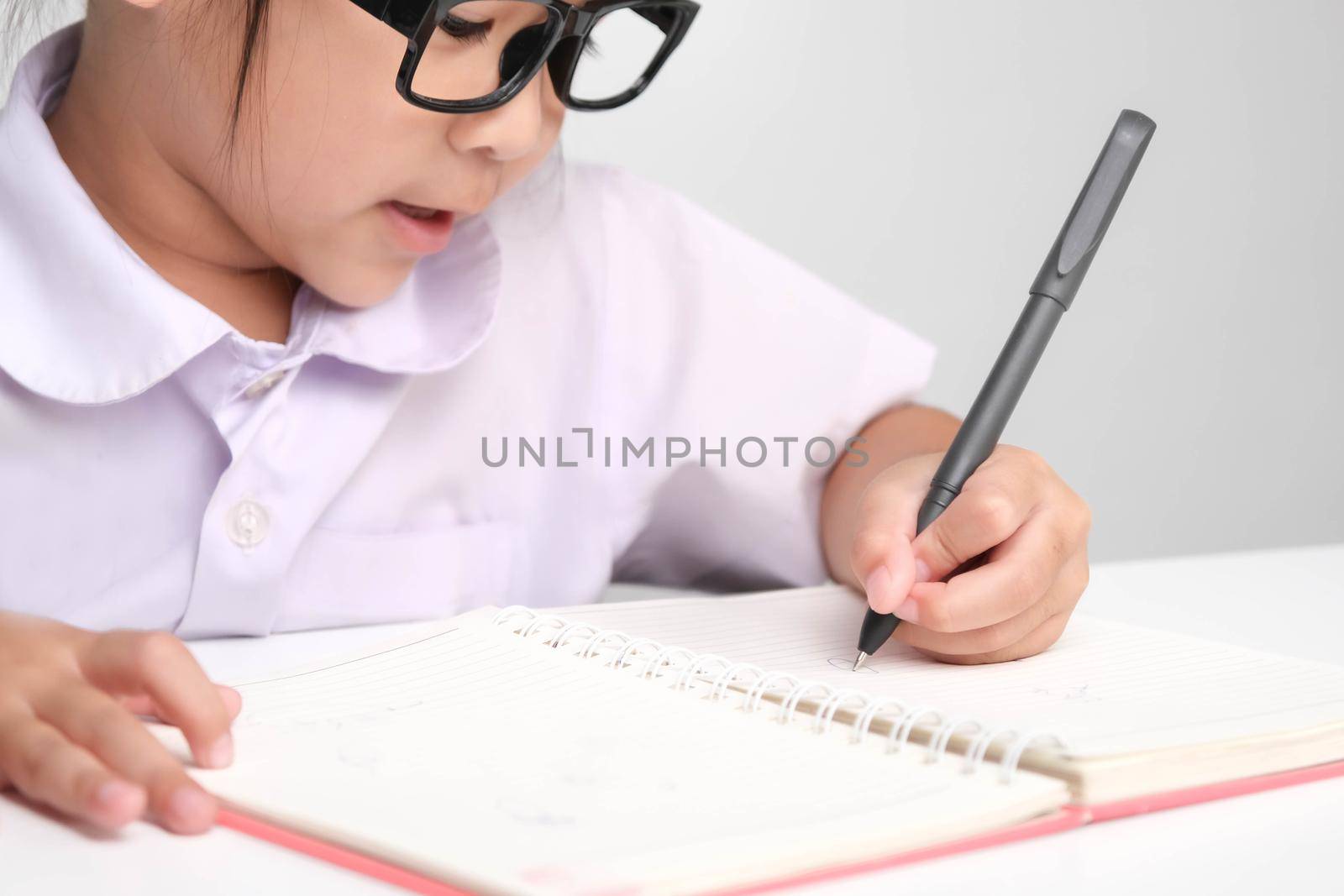 Small businesswoman taking notes while working in the office. Children and business concepts by TEERASAK