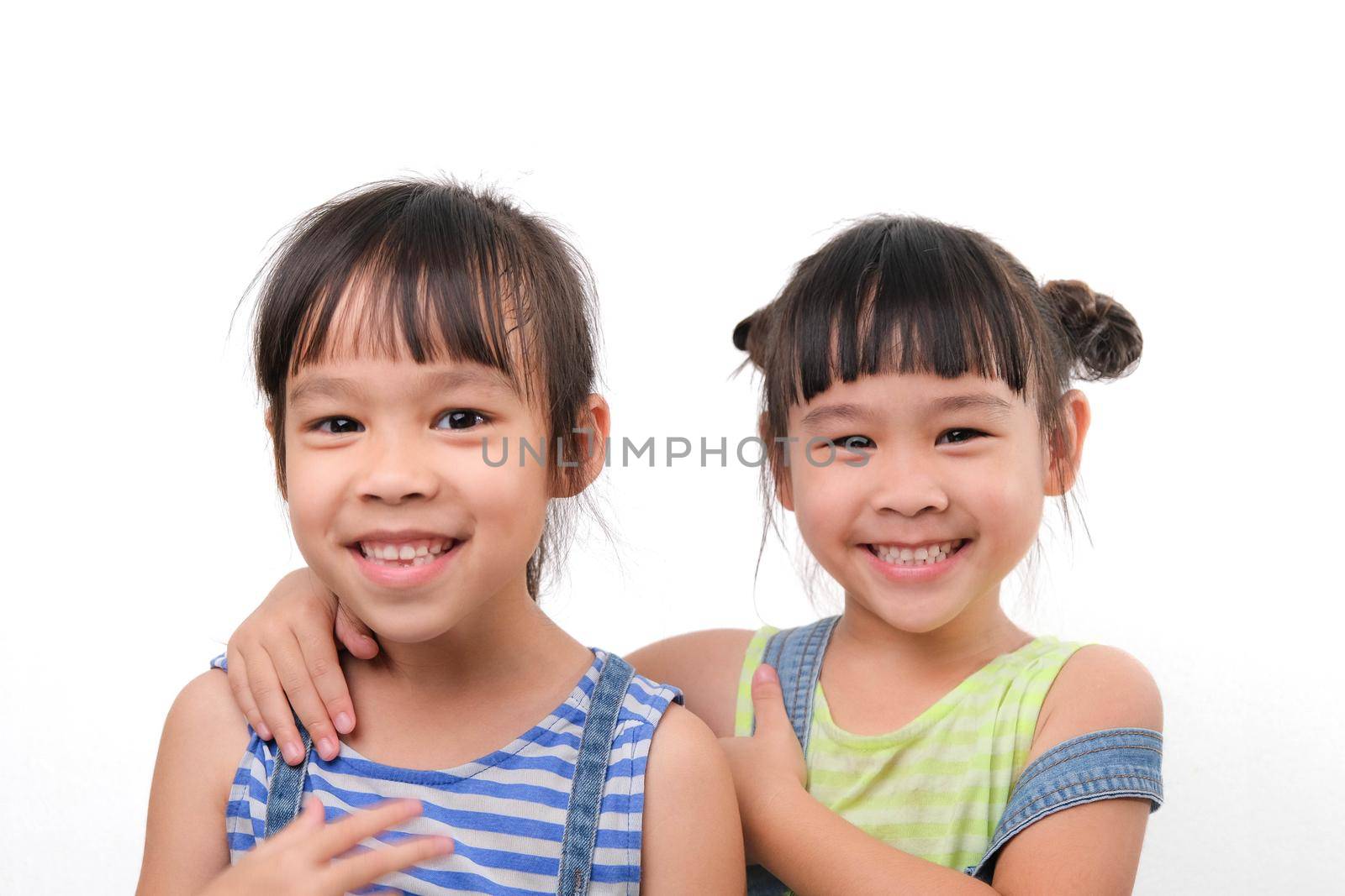 Two little sisters hugging and looking at camera isolated on white background. Two pretty little girls sisters happily cuddle and laugh. friendship and love concept. by TEERASAK