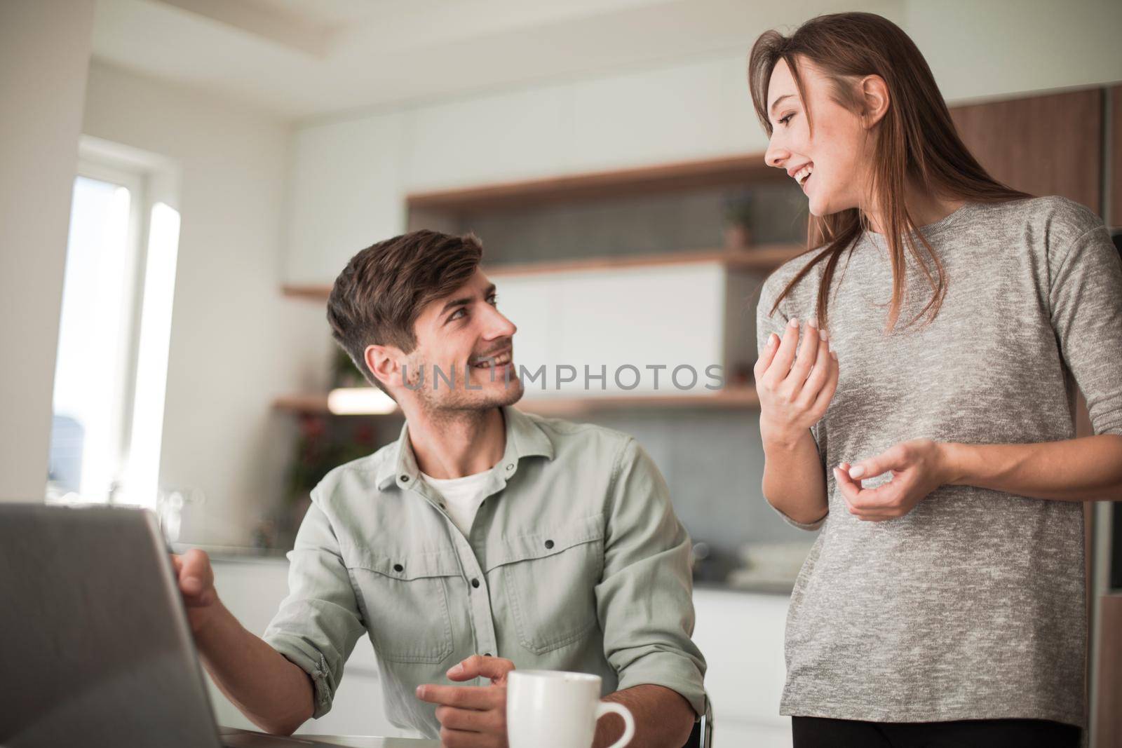 Young couple looking discussing online news in the kitchen by asdf