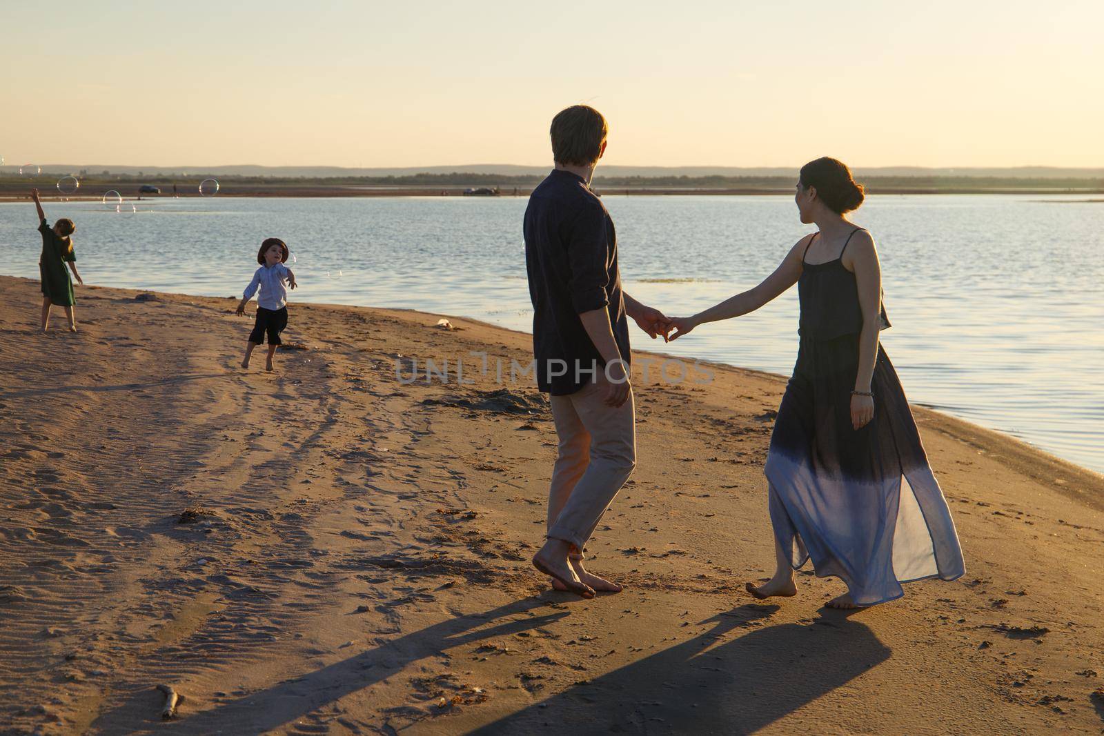 A family with two children are walking along a wild evening beach.