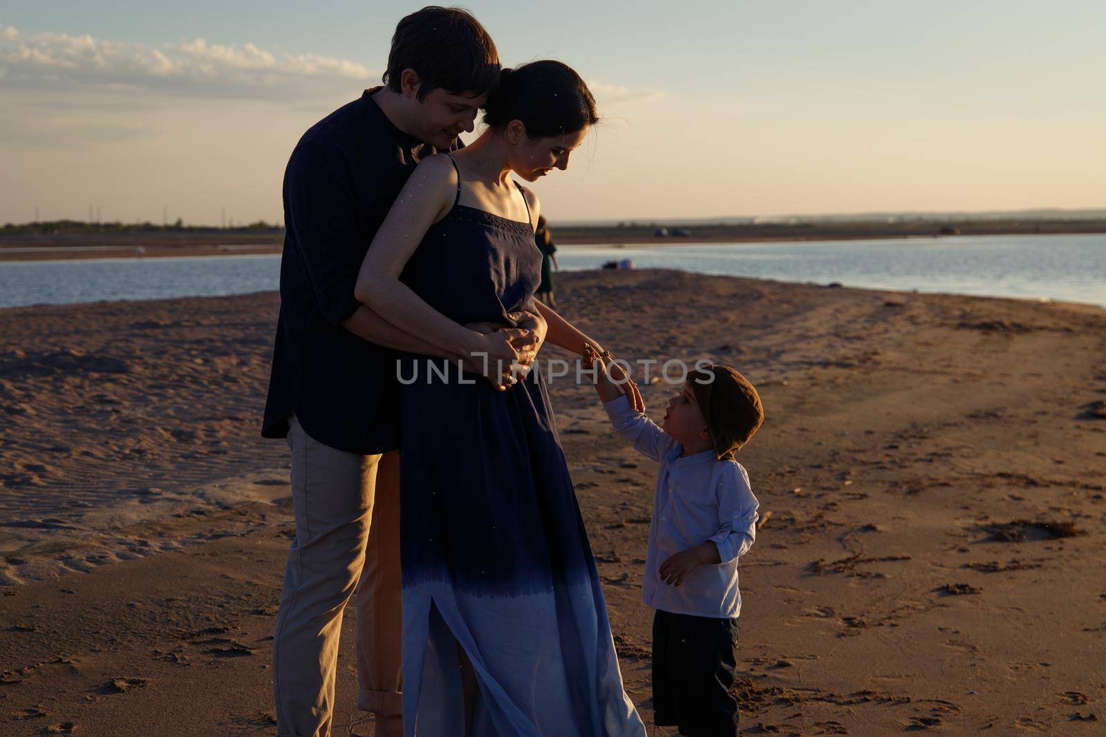 A family with children are walking along a wild evening beach.