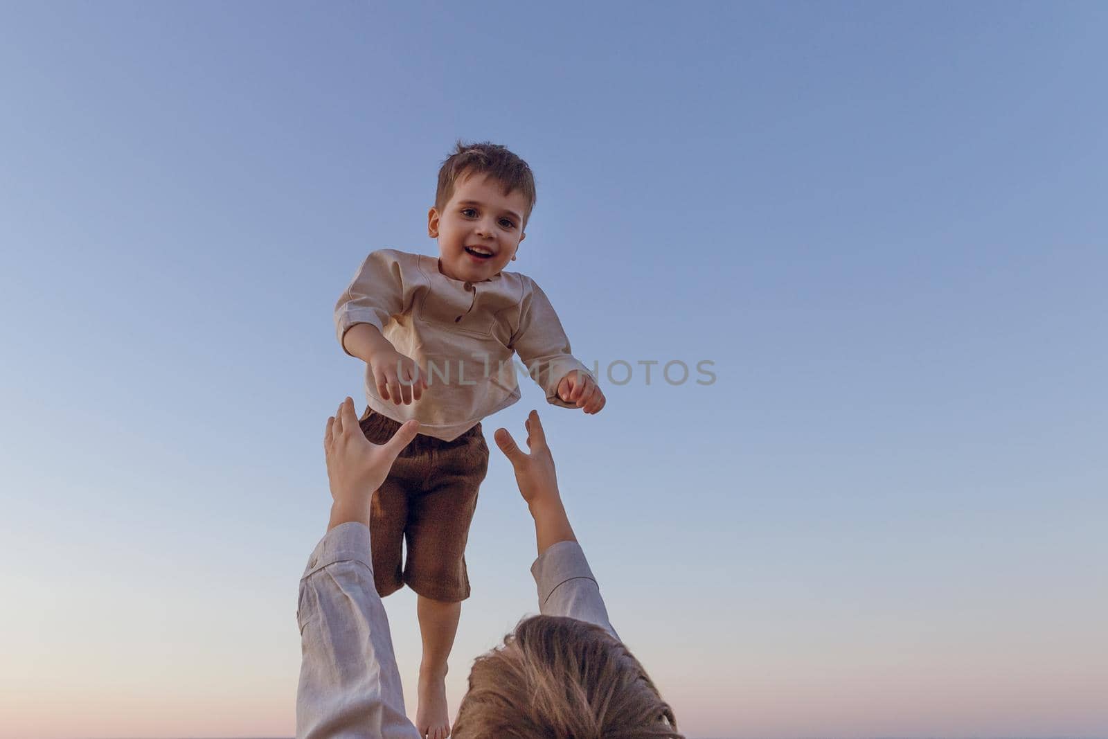 Father fun throws up son in the air. Happy joyful kid.