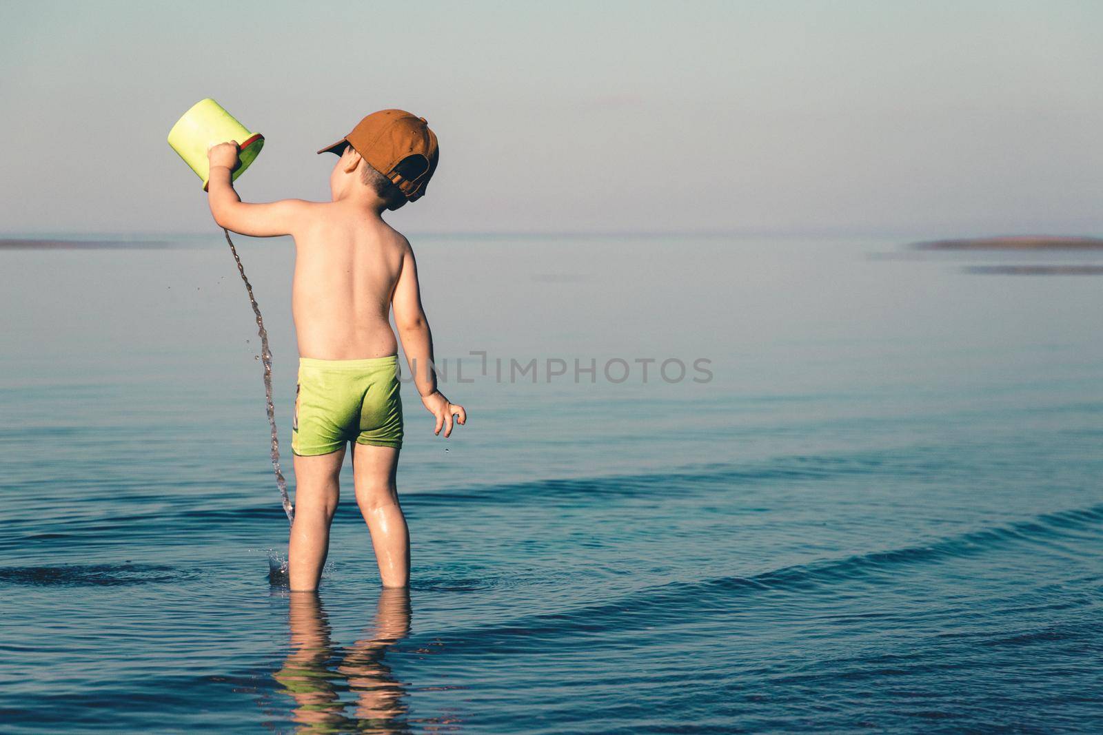 Boy playing in the sea with water and a bucket by Rom4ek