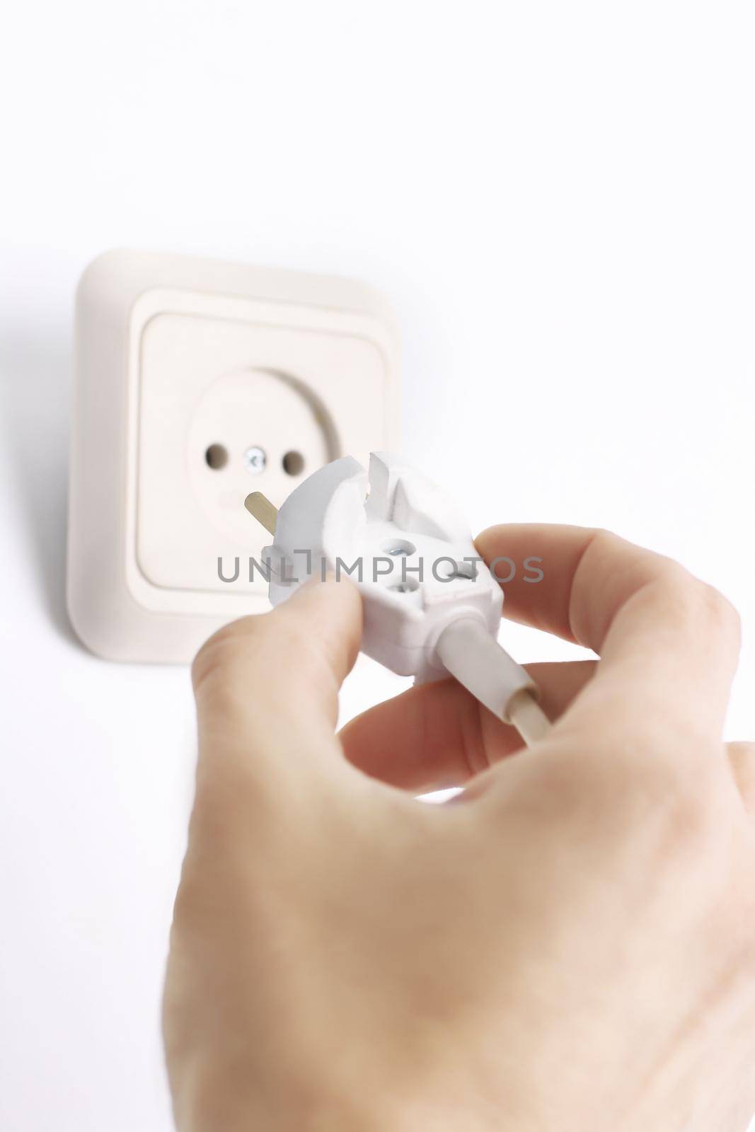 Hand inserting green electrical plug into outlet .