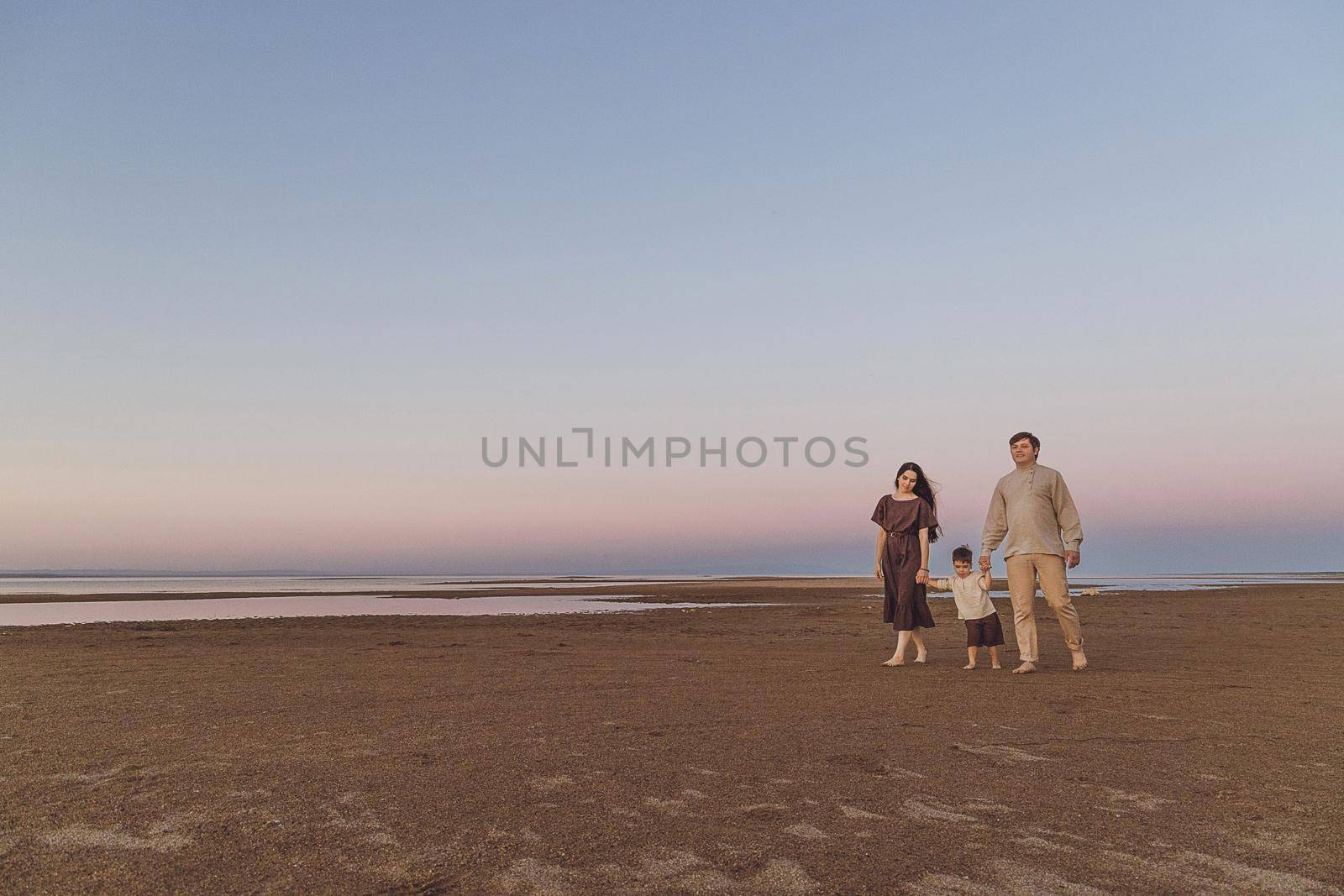 Beach Sunrise with family and dog walking down the beach. Family look linen clothes. Copy space.