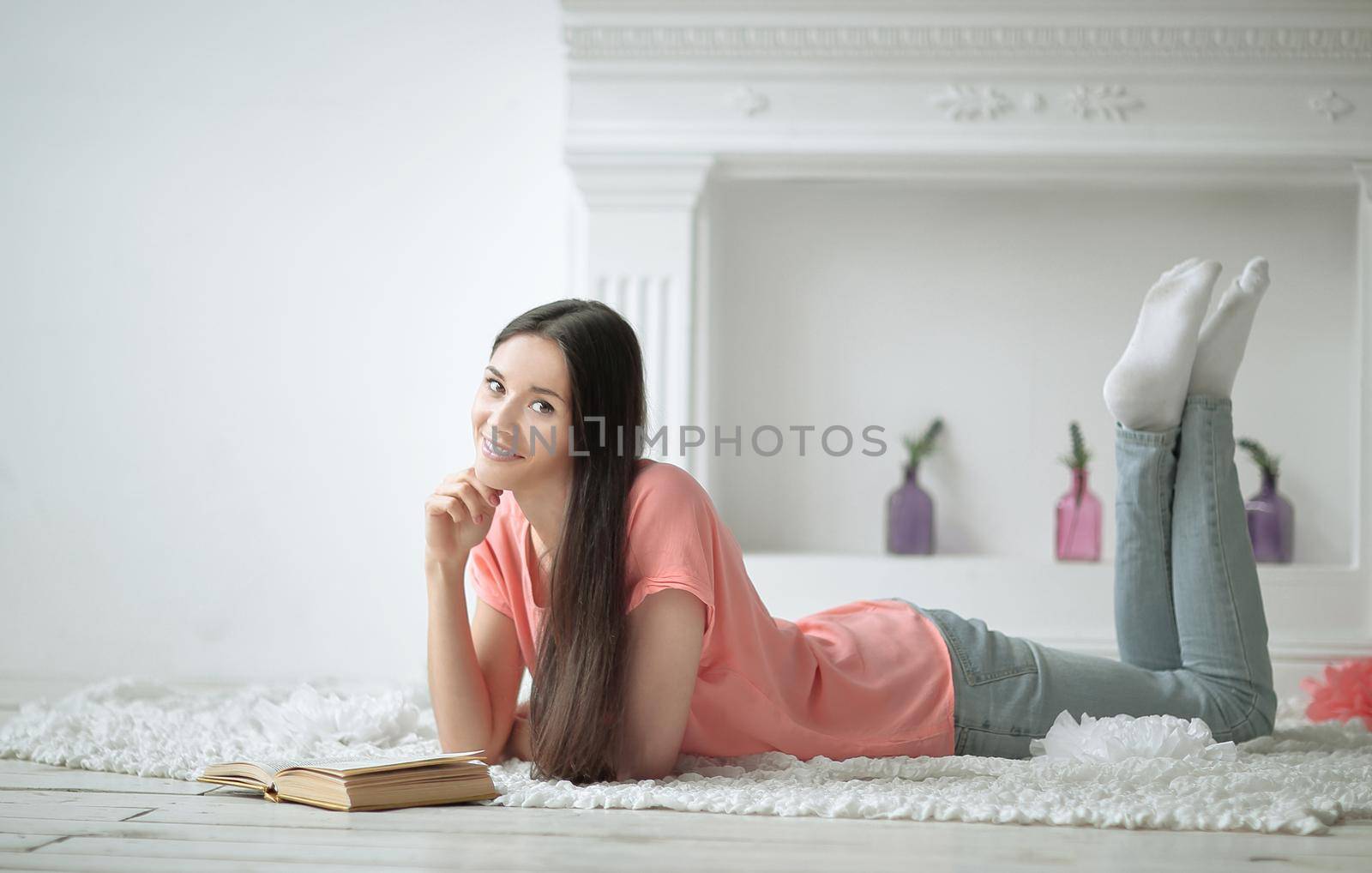 portrait of young girl reading book lying on floor in living room.