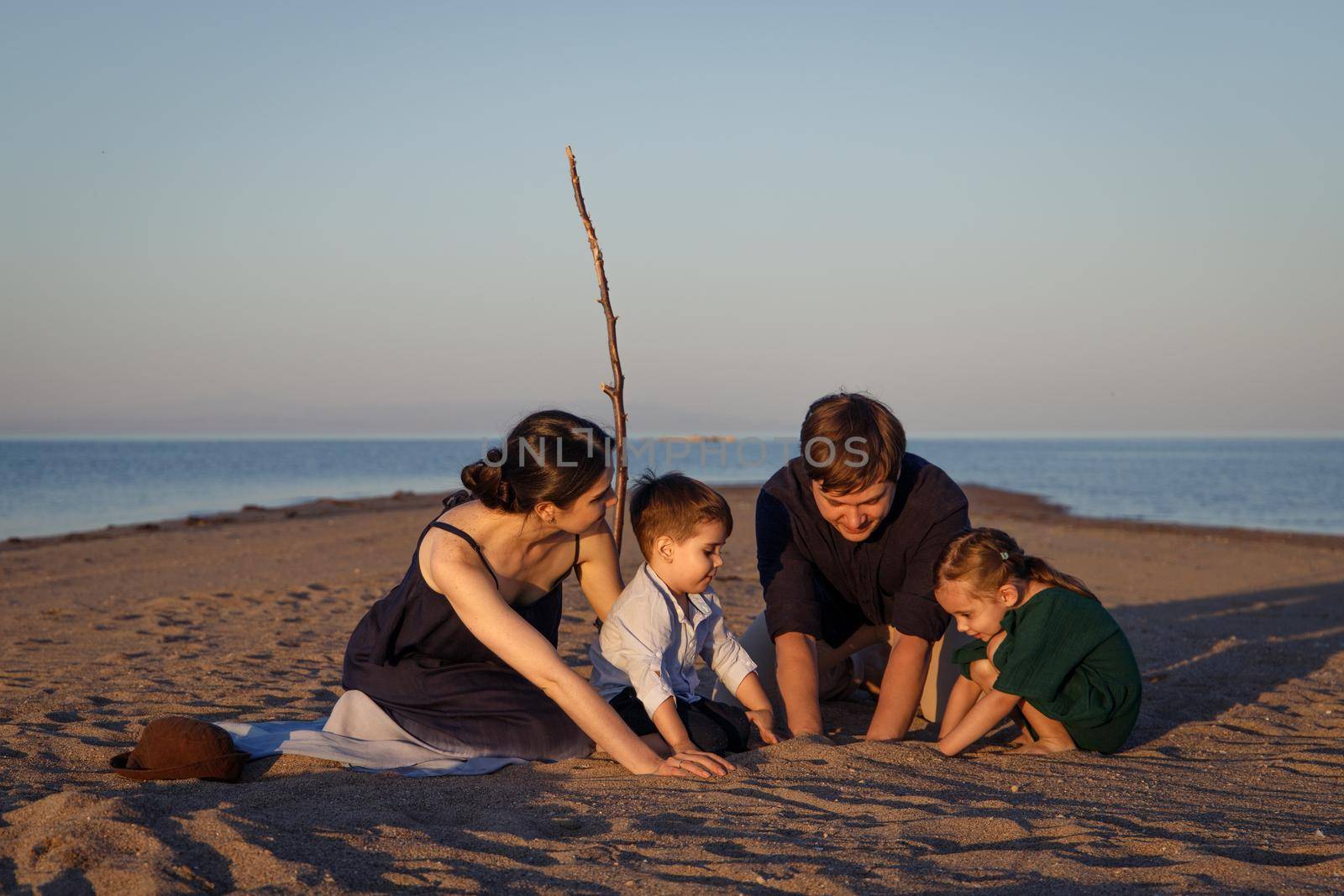 Young family with 2 children playing on the beach in a desert island.
