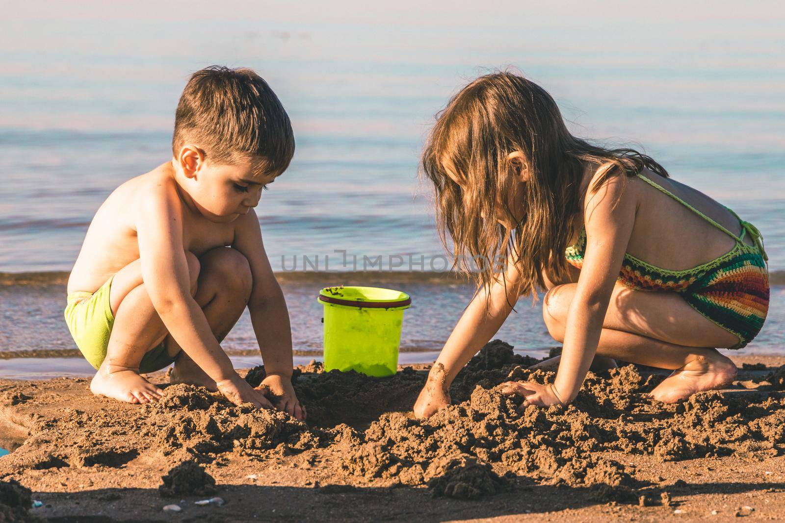 Brother and sister 3-5 years old playing with sand on the seashore.