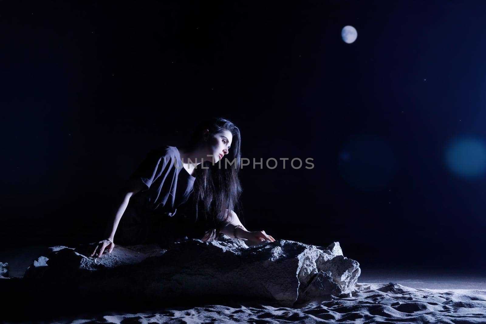 Depressed woman sitting on a stone in dark night. loneliness, sad, emotion concept.