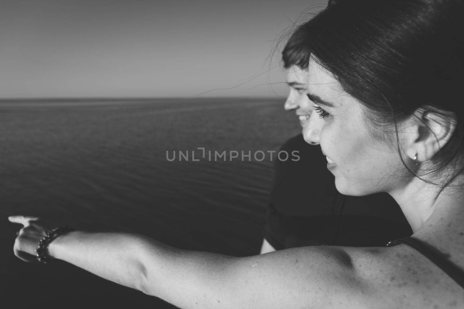 Close-up black and white portrait of a couple in love on the background of the sea in the sunset lighting. Selective soft focus