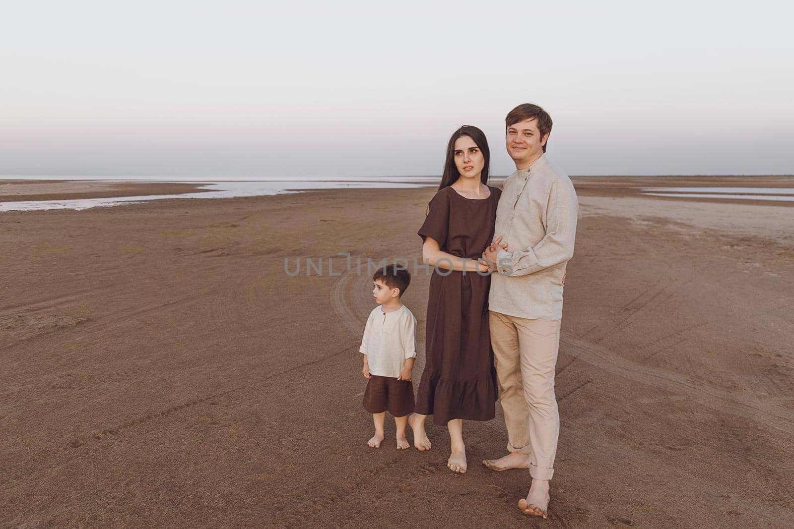 Family look of natural linen clothing on the evening beach. Copy space.