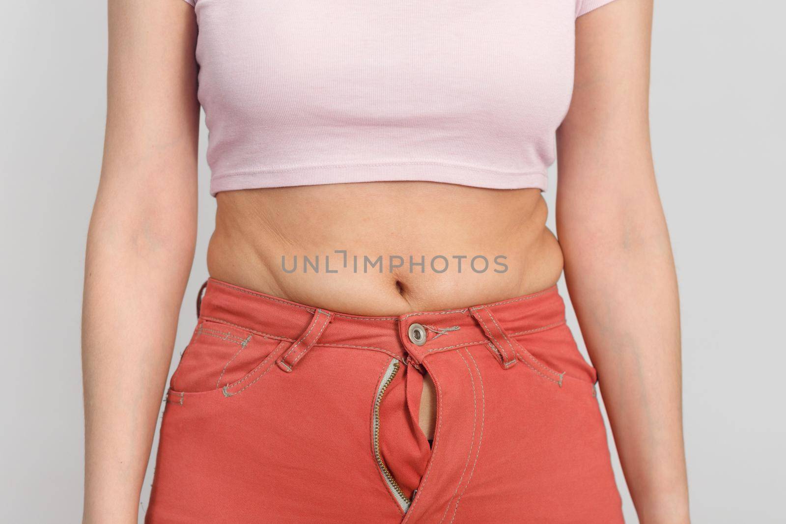 Close-up of belly of a slightly overweight young woman. Diet, overweight, obesity concept.