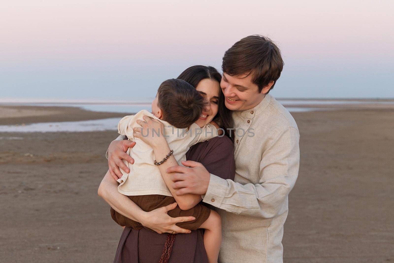 Family hugs on the evening beach. Family look linen clothes.