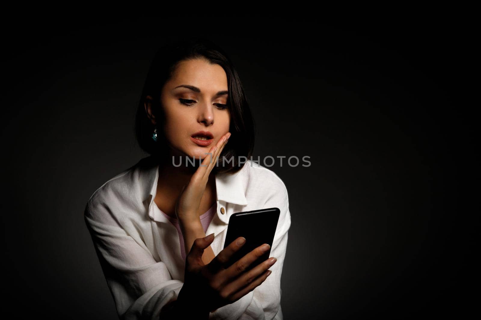 Low-key portrait of beautiful woman using mobile phone late night sleepless in the dark with smartphone and internet by Rom4ek