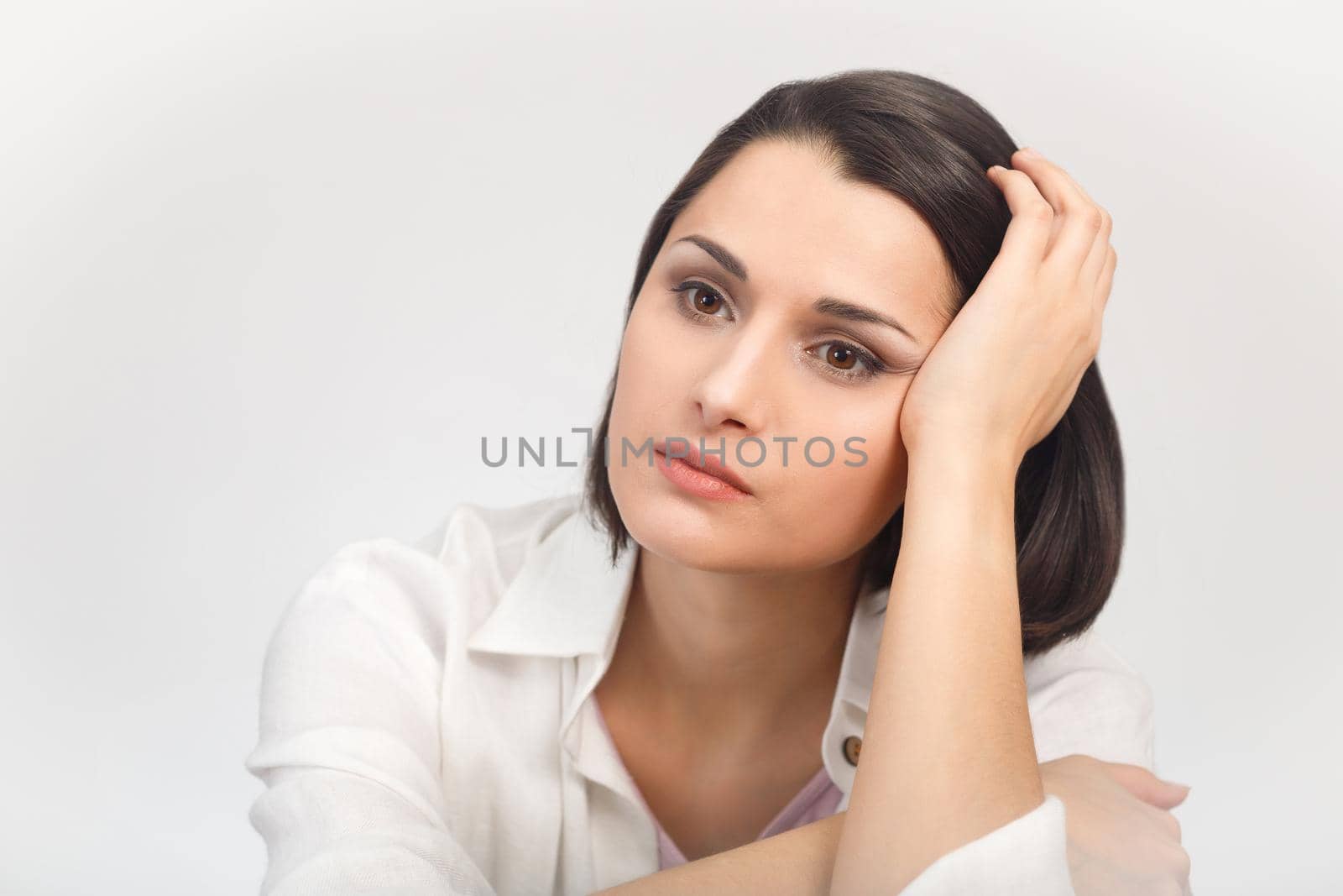 High-key studio portrait of a young sadness woman in light clothes looking into the distance.
