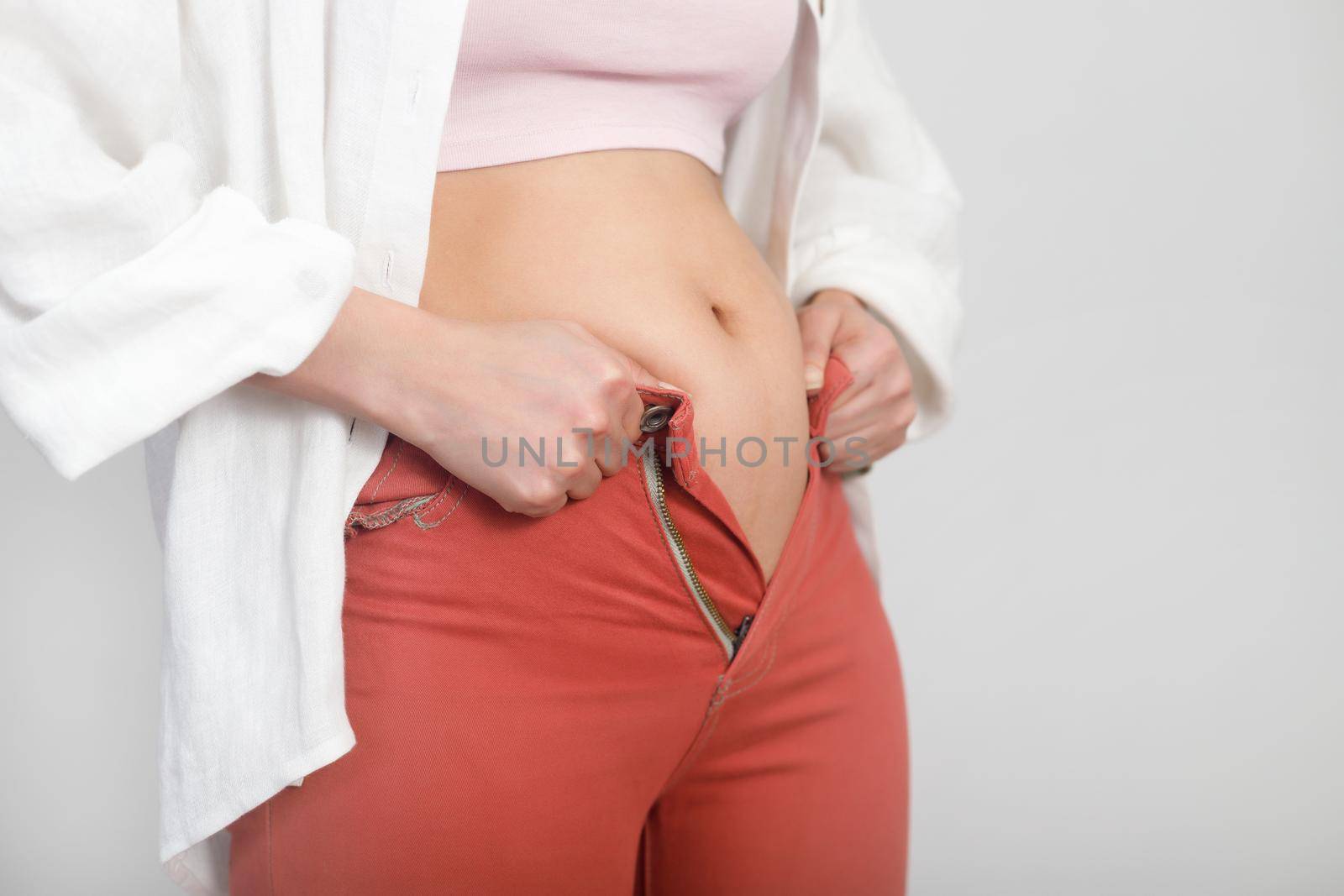 Close-up of belly fat woman can not fasten a zipper on jeans. Diet, overweight, obesity concept by Rom4ek