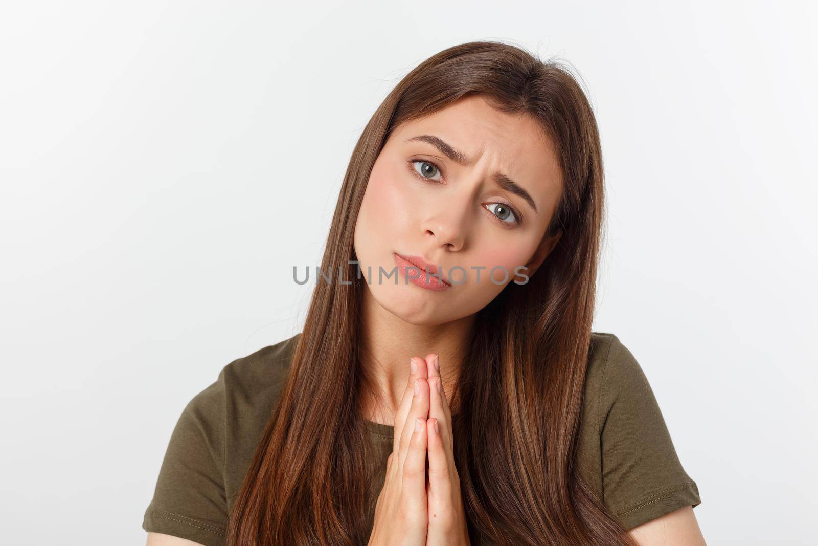 Beautiful young woman in casual clothes holding hands together and praying, isolated on white
