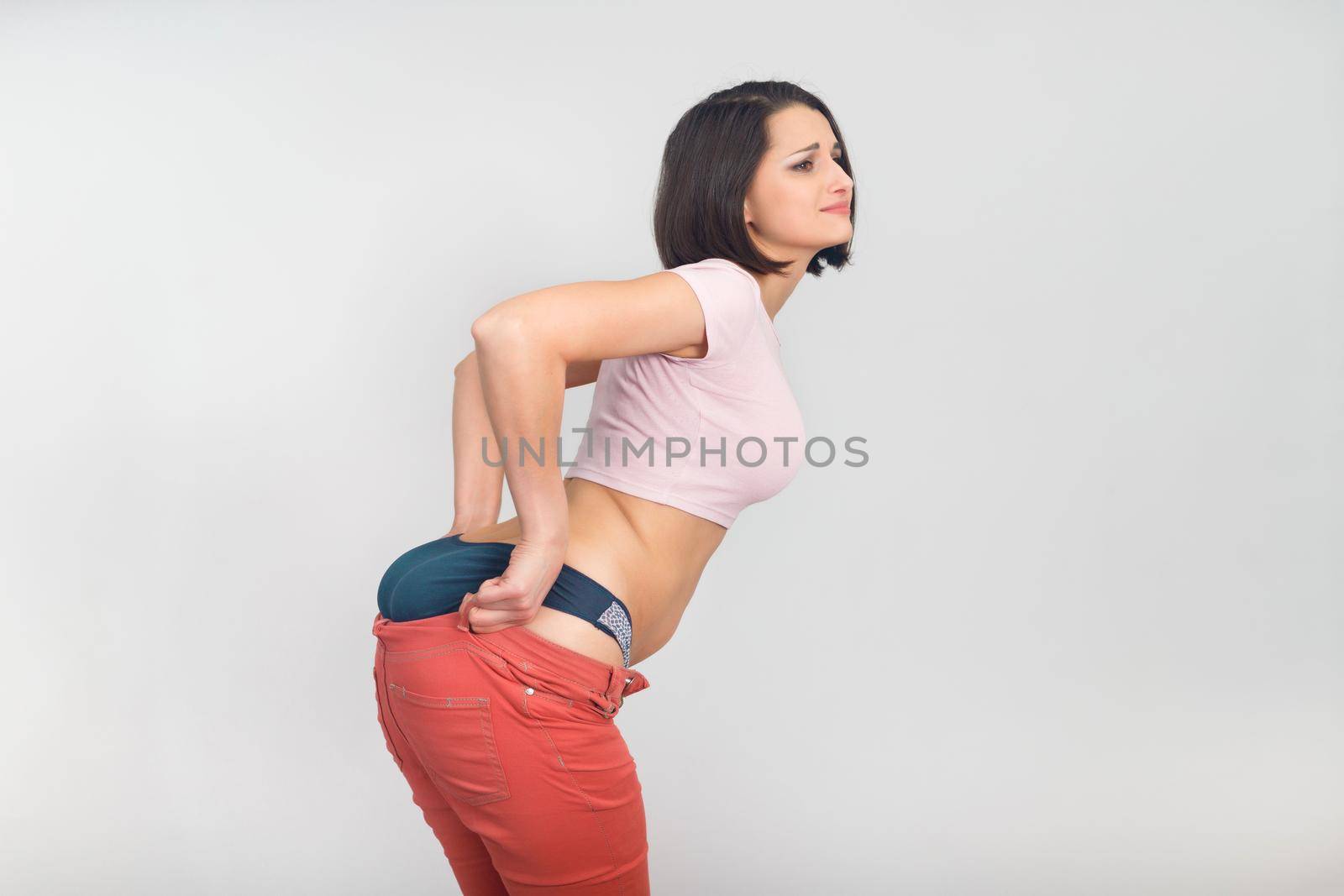 Upset woman pulls on her summer pants. Diet, overweight, obesity concept