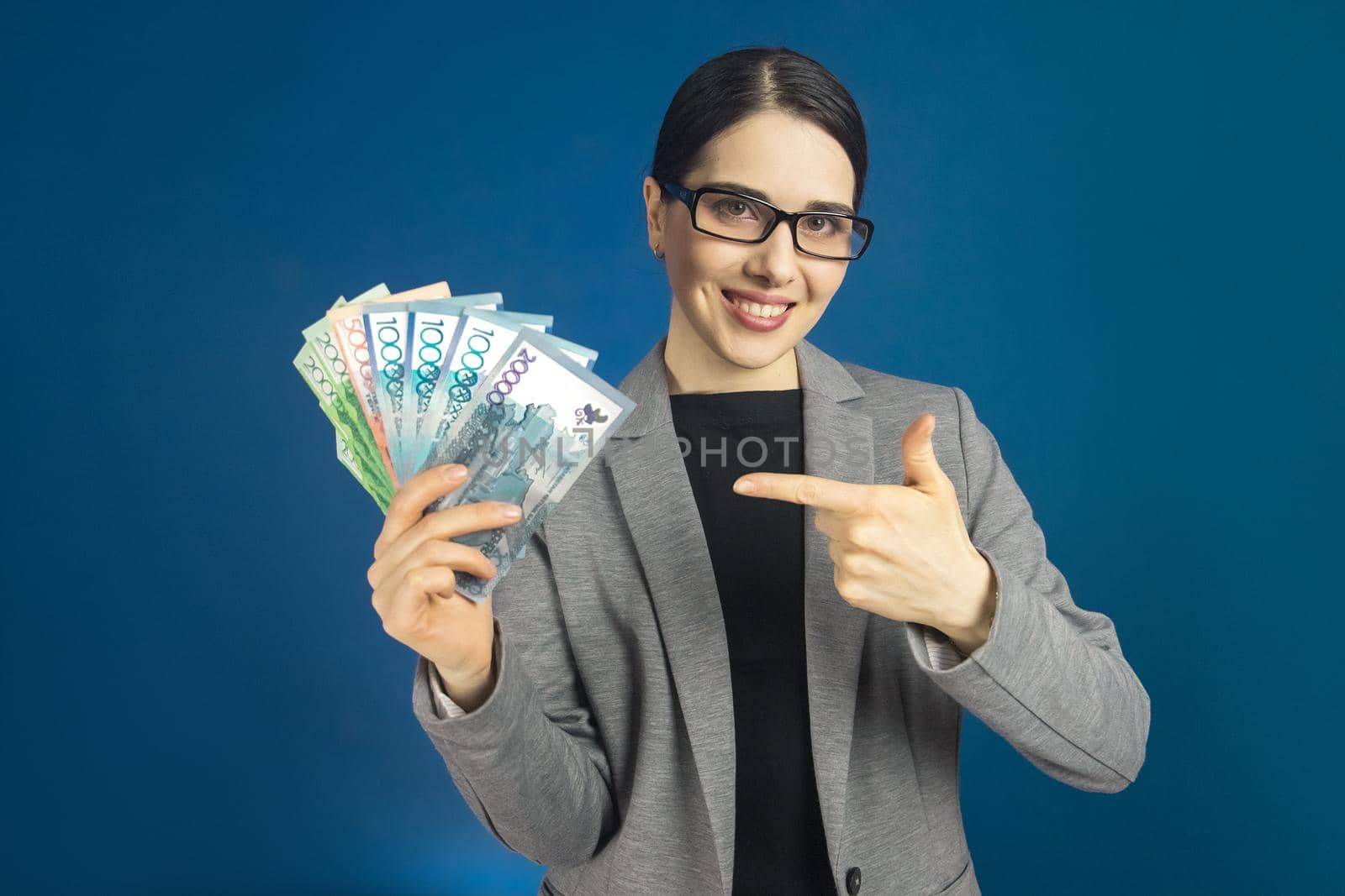 Beautiful young woman in glasses holds a lot of tenge money in her hands by Rom4ek